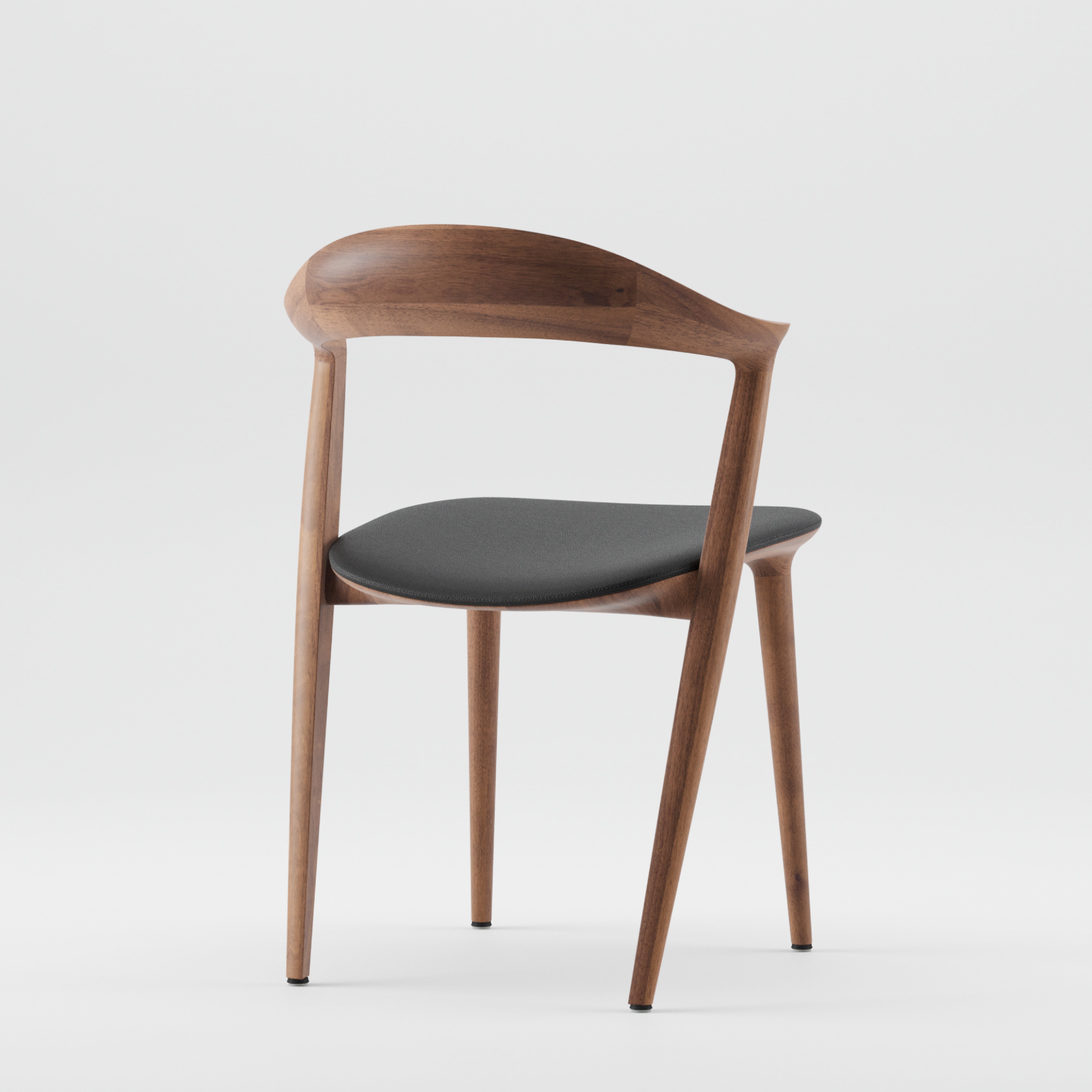 The Addo Chair by Artisan is a modern piece made from solid wood, showcasing a curved backrest and tapered legs. With a dark cushioned seat against a white backdrop, it emphasizes sustainability through eco-friendly materials and natural oils.
