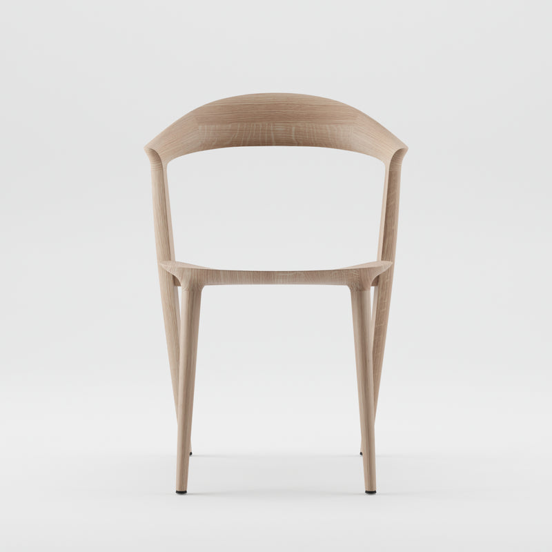 The Addo Chair by Artisan is a minimalist design featuring a solid wood build with a curved backrest and slender legs. Its smooth, natural wood finish, enhanced by oils, offers a contemporary look against a plain white background.