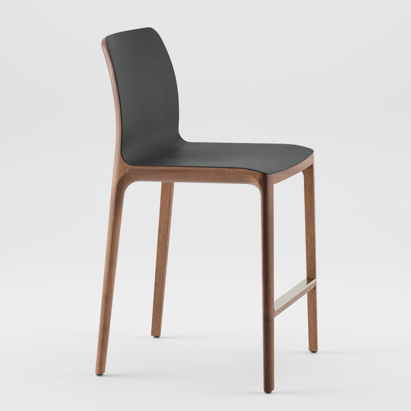 The INVITO Barstool by Artisan is a modern design featuring a sleek black seat with a gently curved back, solid wood legs in a natural finish, and an eco-friendly metal footrest. Set on a plain white background, it embodies elegance effortlessly.