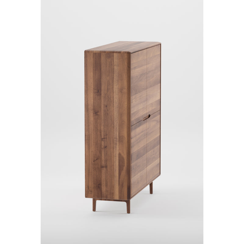 The INVITO Highboard by Artisan is a tall, narrow wooden cabinet made from solid wood with a minimalist design. Its smooth finish is enhanced by natural oils, and it features a vertical door with subtle handles. The eco-conscious construction sits on short legs against a plain white background.