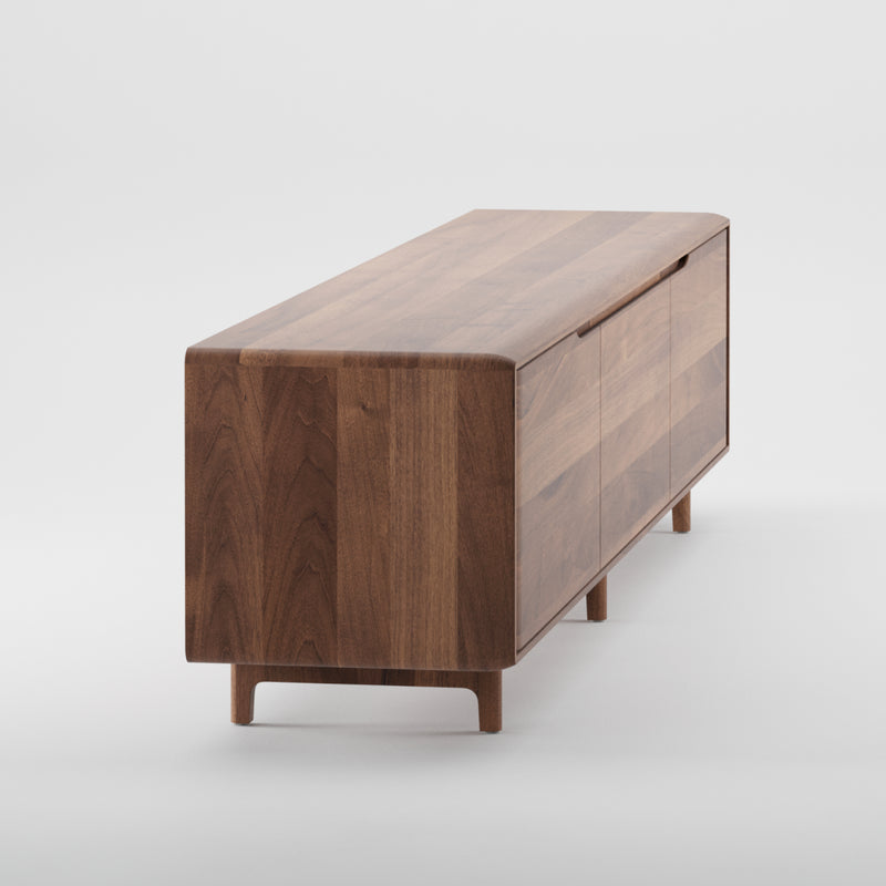 The Artisan INVITO Lowboard is a mid-century modern wooden sideboard crafted from solid wood with a sleek design, featuring a smooth surface and minimalist legs. It showcases rich brown wood grain finished with natural oils and offers cabinets and drawers in a handle-free design.