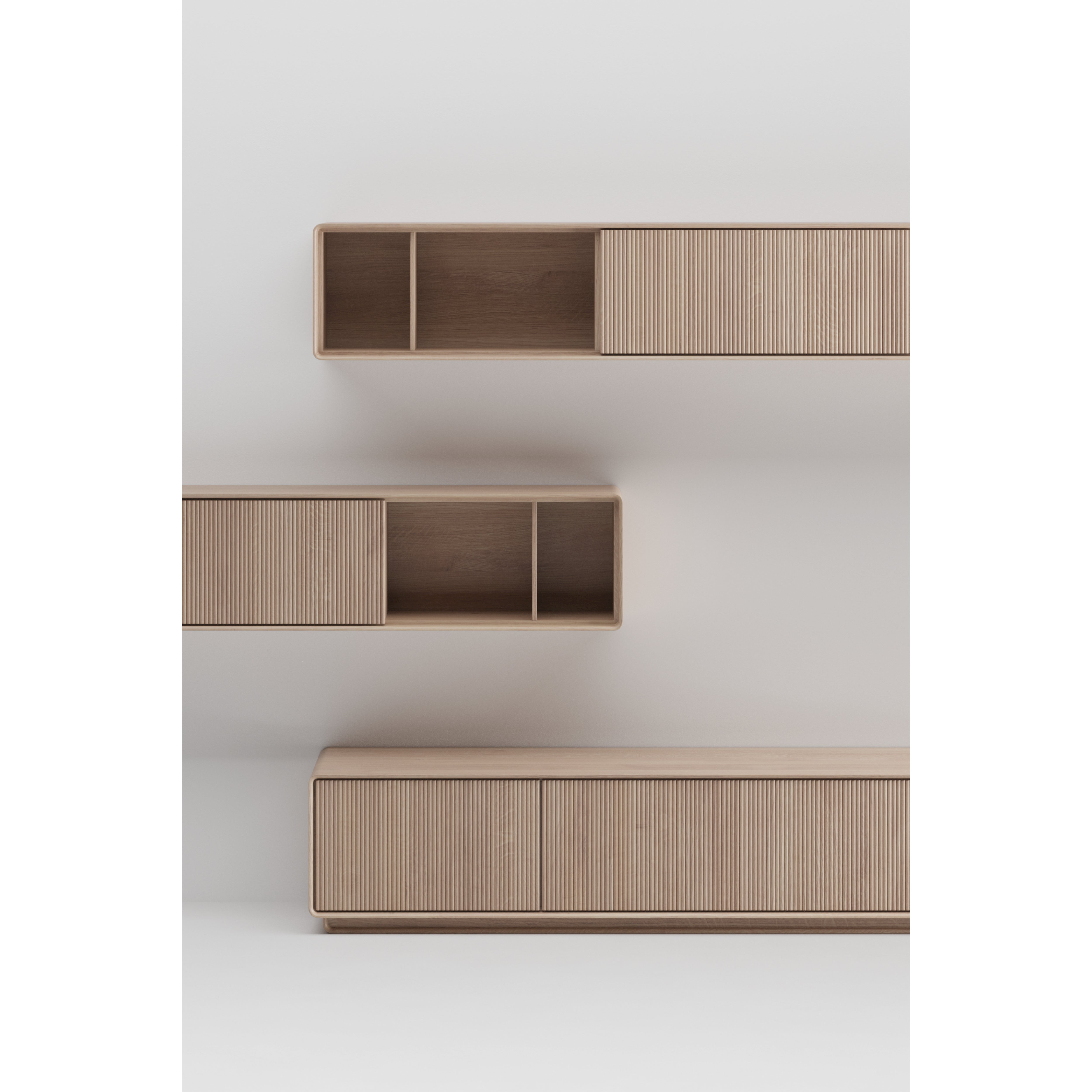 The Artisan JANTAR Modular System features minimalist wooden storage units crafted from solid wood and mounted on a white wall. The design includes two top units with open/closed sections and a fully closed bottom unit. A light finish with natural oils adds an eco-friendly touch.