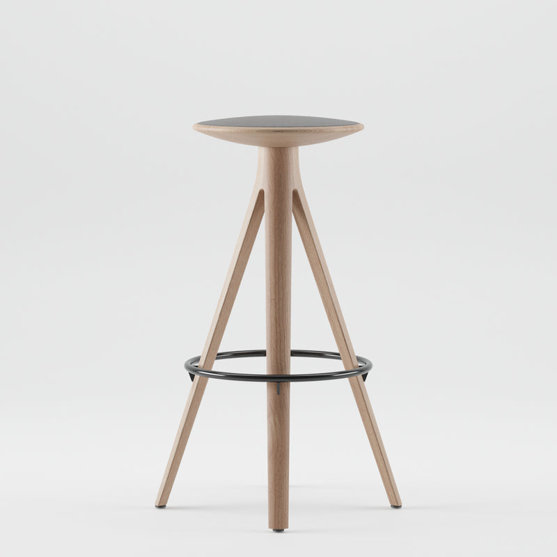 The KALOTA Barstool by Artisan features a sleek, modern design with a solid wood, three-legged frame and a round seat. Natural wood tones, enhanced by natural oils, contrast the black metal footrest. Its minimalist and eco-friendly style stands out against a plain white background.