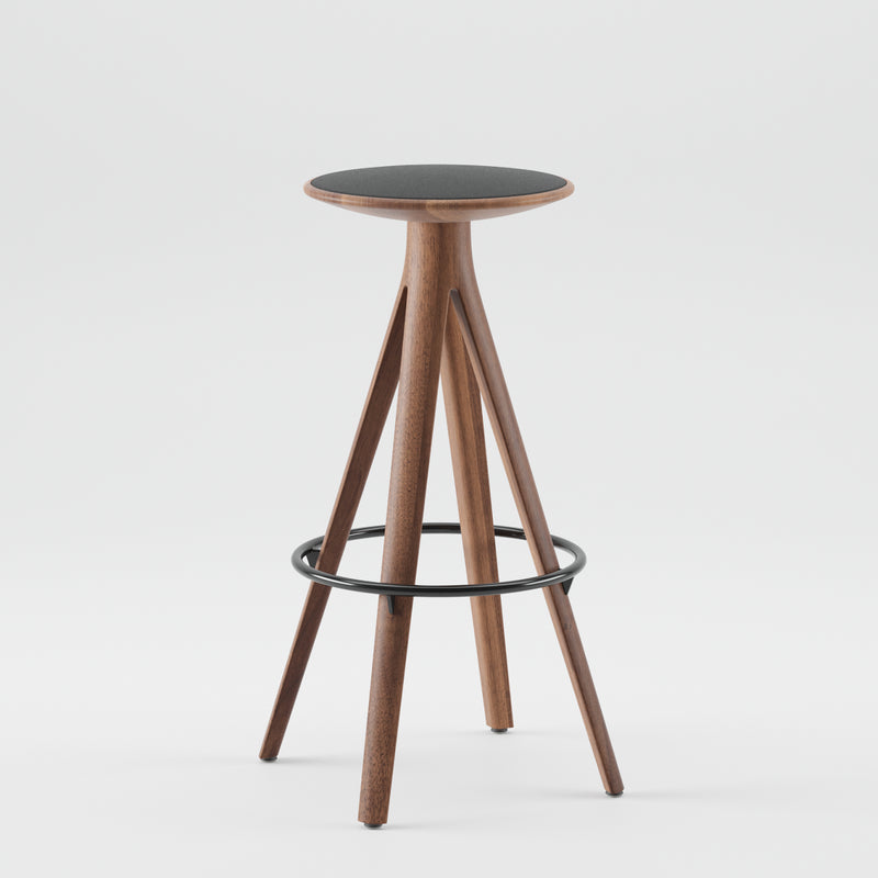 The Artisan KALOTA Barstool is a tall, modern piece crafted from solid wood with a round seat and three angled legs. It features natural oils for an eco-friendly finish and a circular metal footrest, all set against a plain white background.