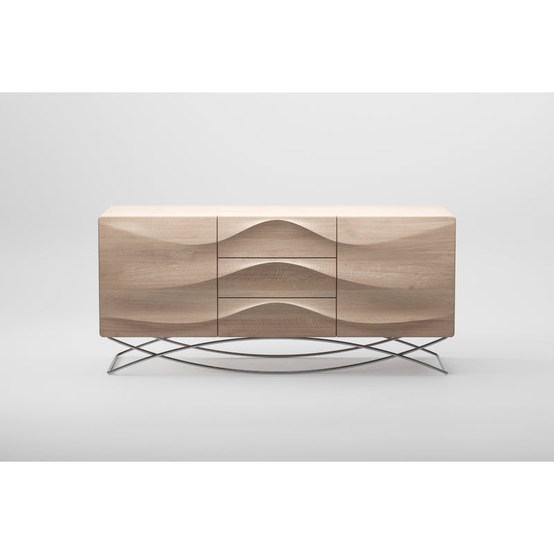 The LASTA Sideboard by Artisan is a sleek, solid wood piece with a minimalist design. It has wavy carved front panels and stands on a criss-cross metal base. Finished with natural oils for eco-friendliness, it presents a striking look against a plain white background.