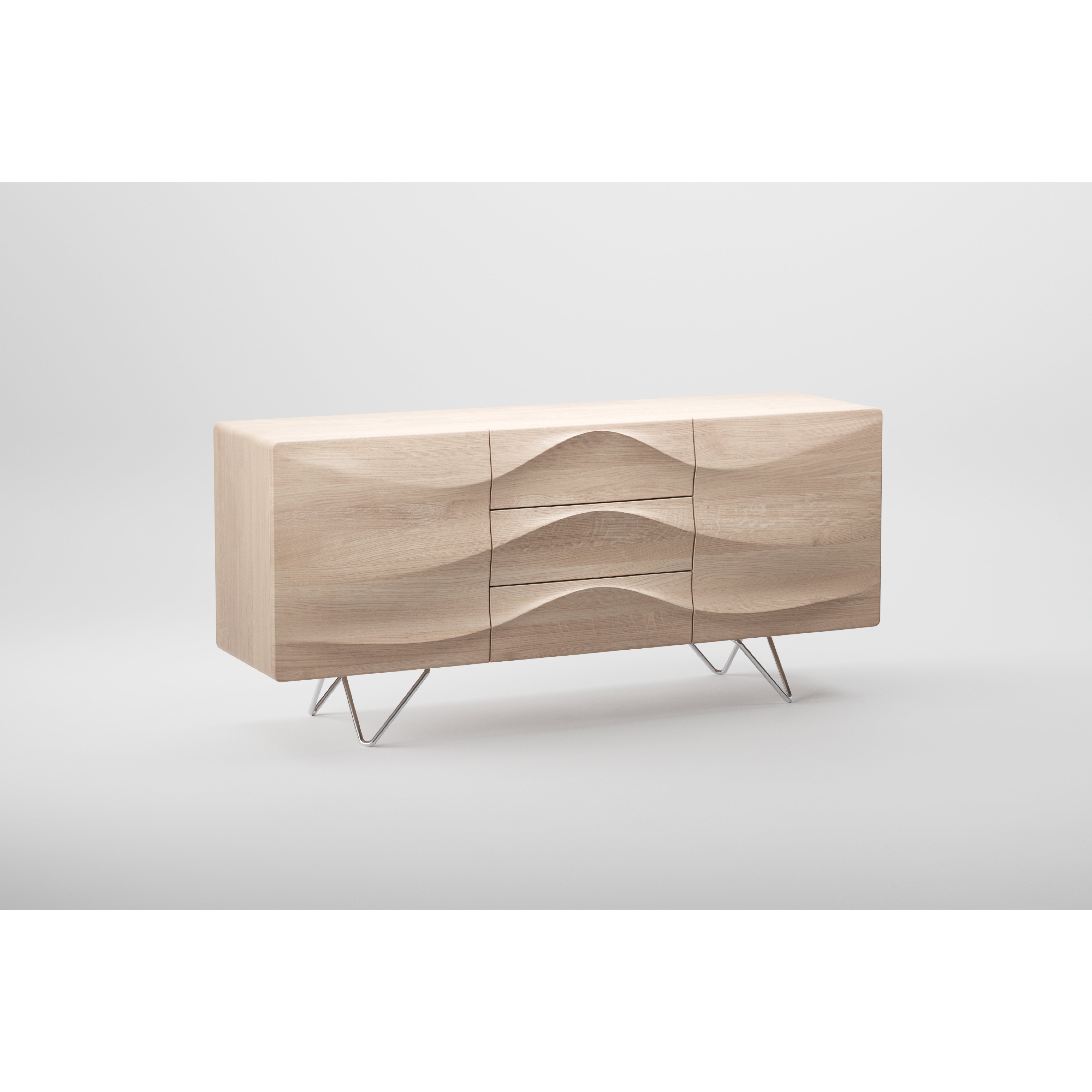 The Artisan LASTA Sideboard is a modern light wood piece crafted from solid wood and finished with natural oils. It features a wavy, sculpted front with three center drawers, two side cabinets, and sleek metal legs, all set against a plain white background.