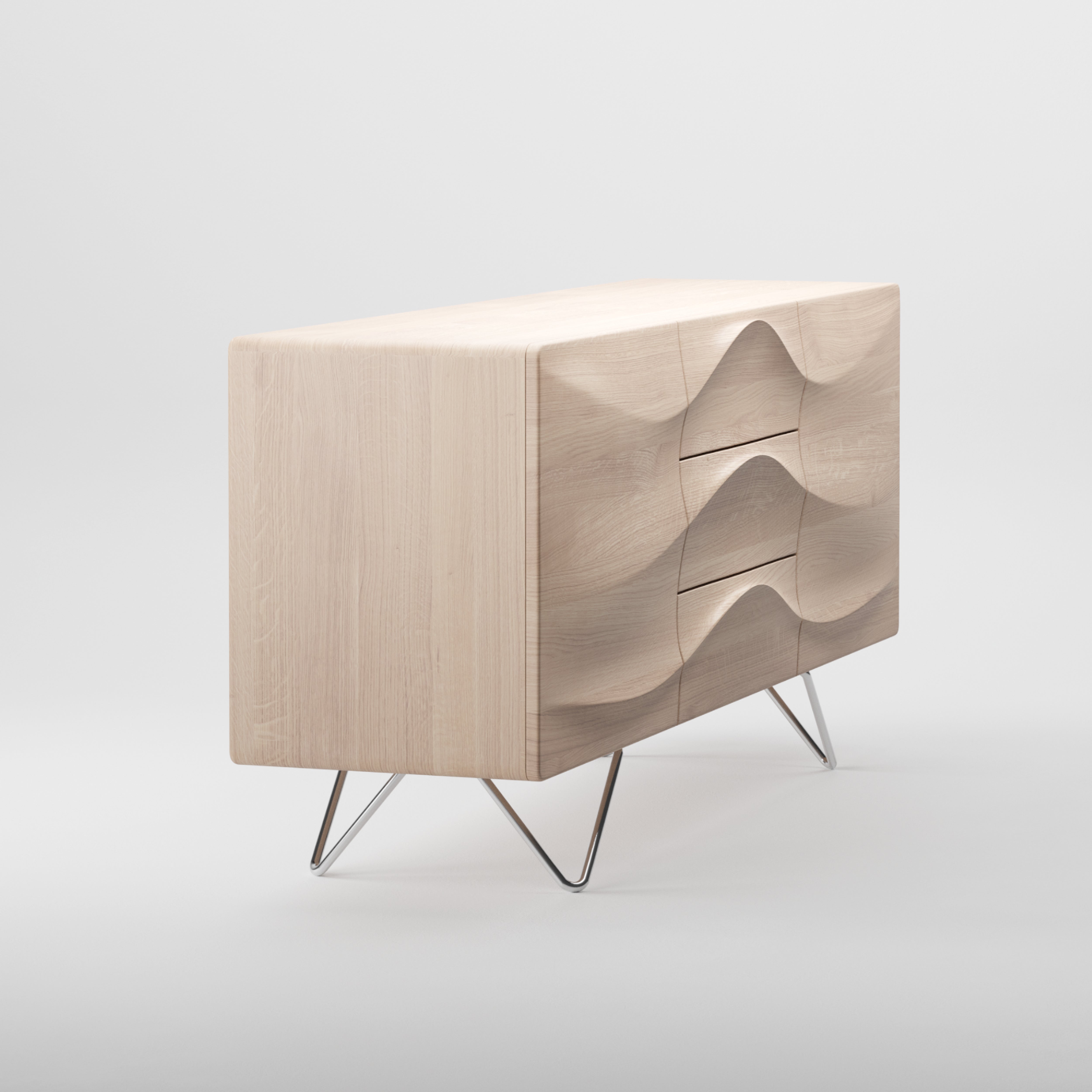 The Artisan LASTA sideboard features a distinctive wave design on its three solid wood drawers. Finished with natural oils, it boasts a light wood hue and rests on sleek metal legs, offering an eco-friendly charm against a plain white backdrop.