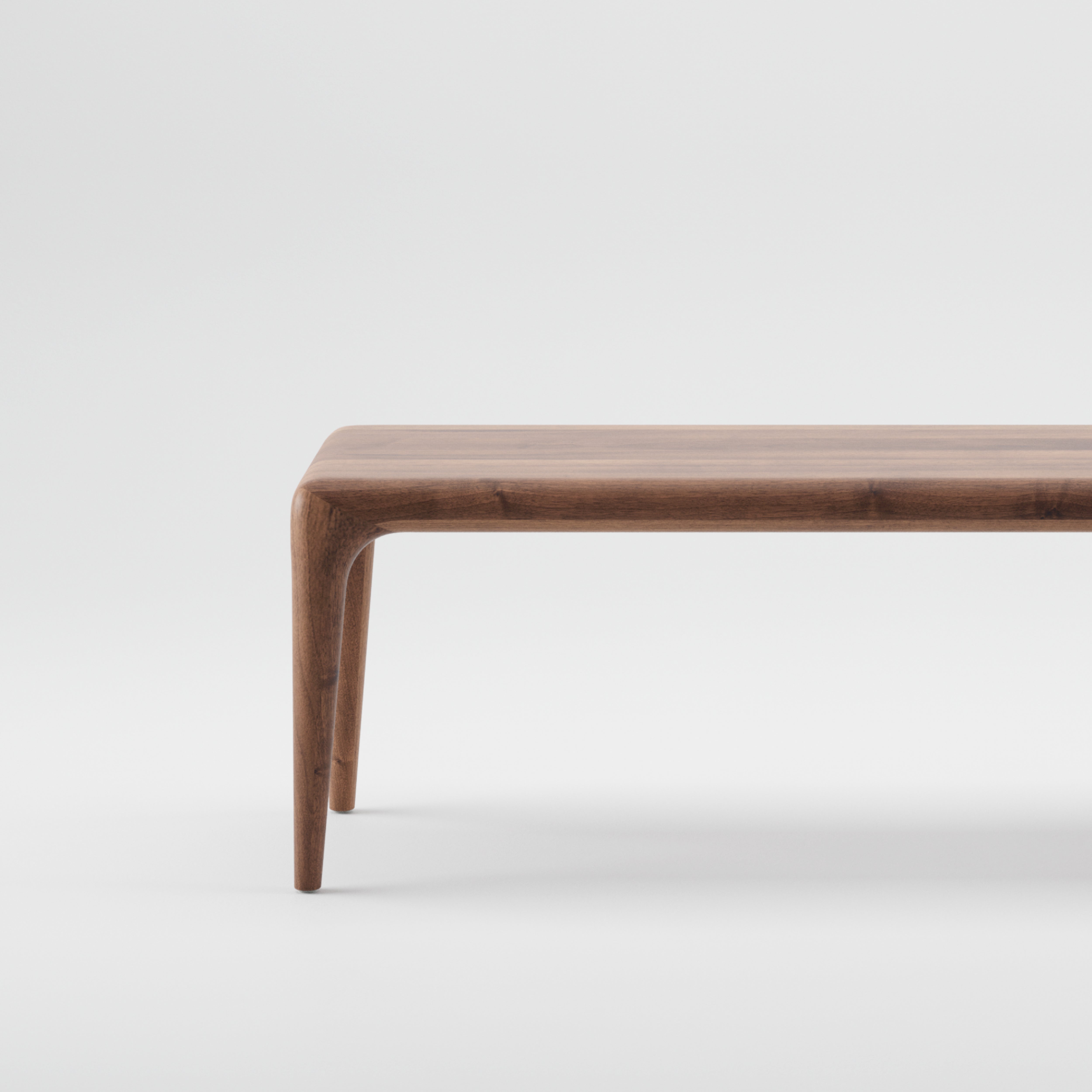 The LATUS Bench by Artisan stands against a plain white background. Made from solid wood and finished with natural oils, it has sleek, curved legs and a polished finish that highlights the natural grain, embracing minimalist design with environmentally-friendly materials.