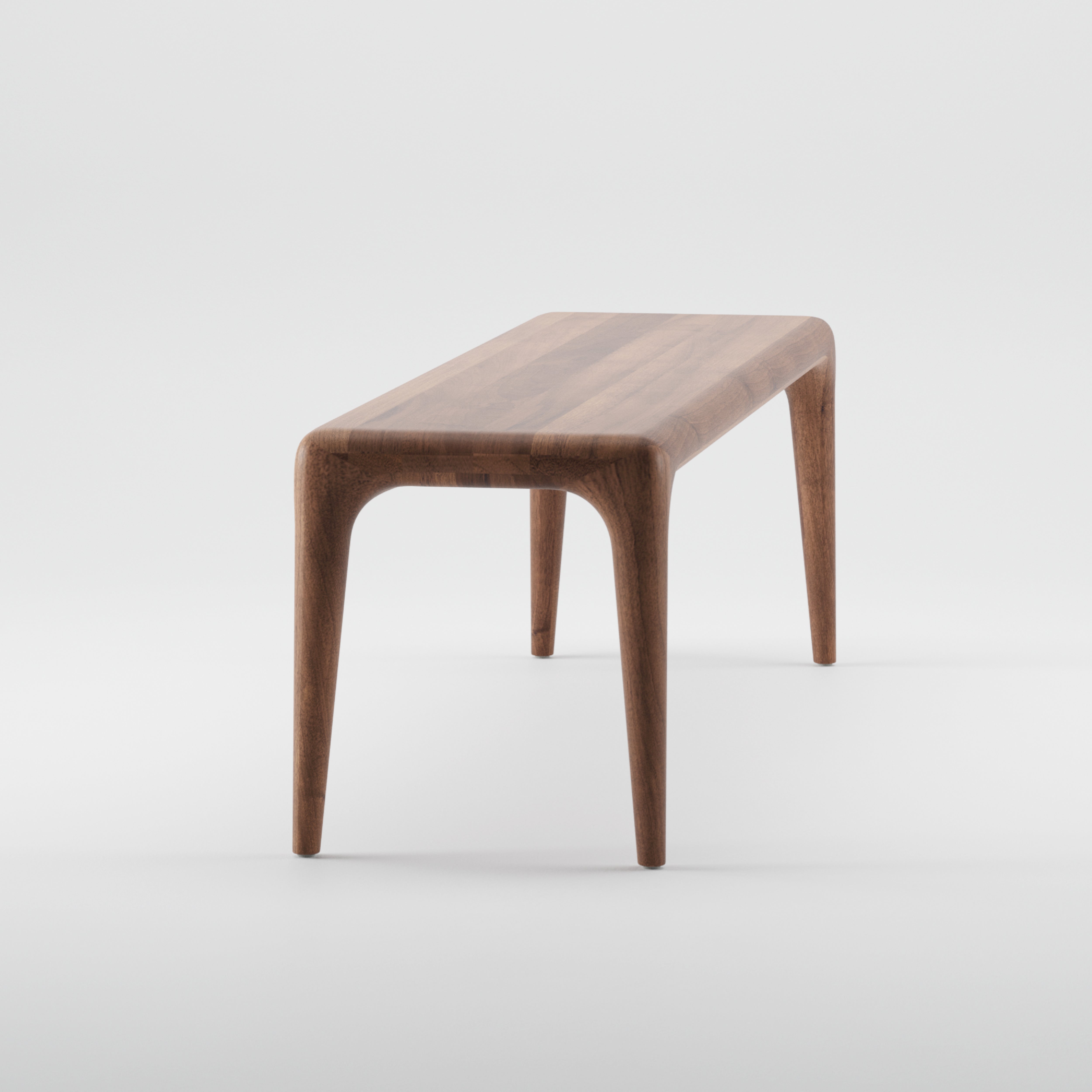 The LATUS Bench by Artisan is a sleek wooden piece crafted from solid wood with a smooth finish and rounded corners. Enhanced by natural oils, it features four tapered legs and a minimalist design, shown against a plain white background.