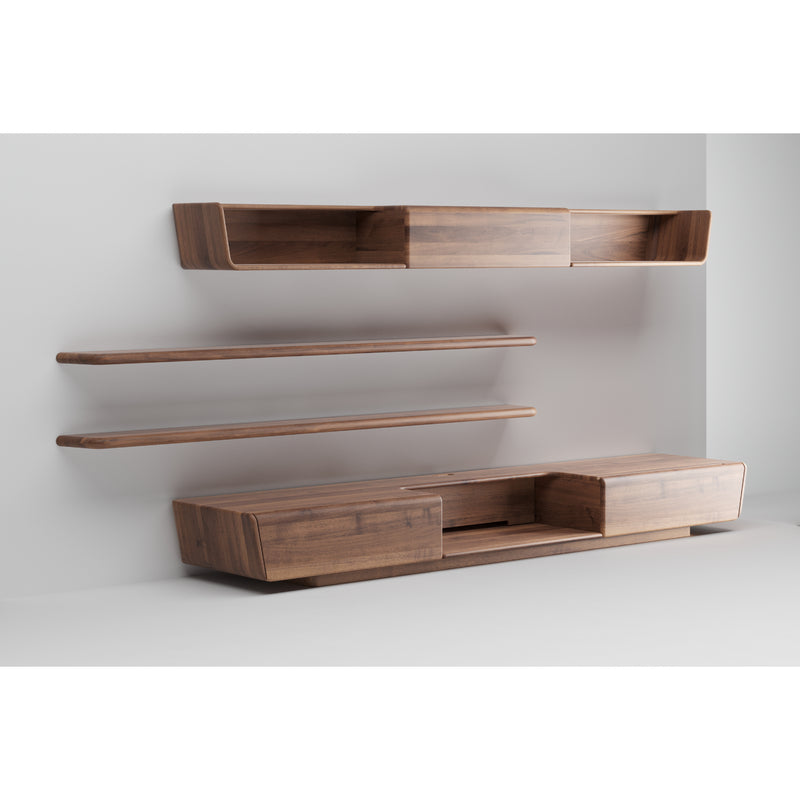 The LATUS Modular System by Artisan is a minimalist wooden wall unit crafted from solid wood with a natural finish. It includes two open shelves, a closed box with sliding doors, and a base cabinet also with sliding doors, all mounted on a light gray wall using eco-friendly materials.