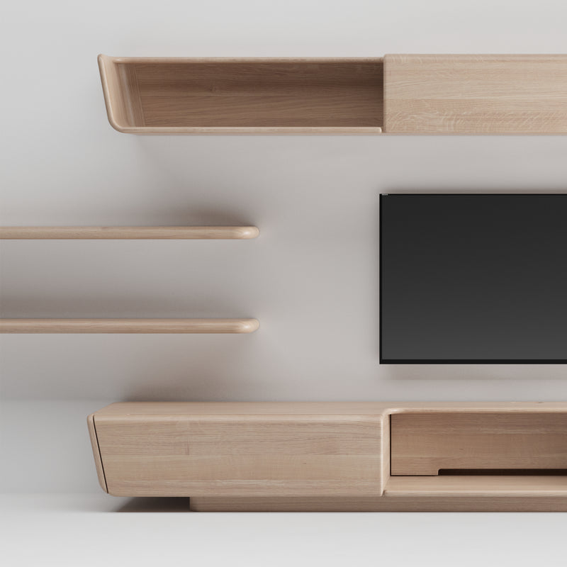 The minimalist living room setup features the Artisan LATUS Modular System, with a wall-mounted flat-screen TV surrounded by solid wood shelves and cabinets made from eco-friendly materials. The design combines open shelving and closed storage, achieving a clean and modern look.