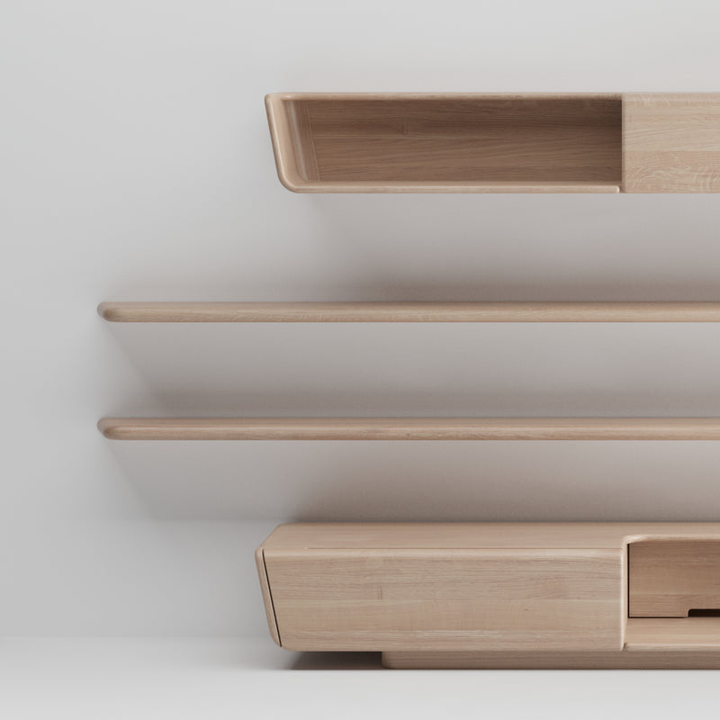 The Artisan LATUS Modular System offers minimalist wooden shelves and a cabinet set against a light wall. Designed with smooth lines and natural wood textures, it provides a modern, elegant look using environmentally-friendly materials.