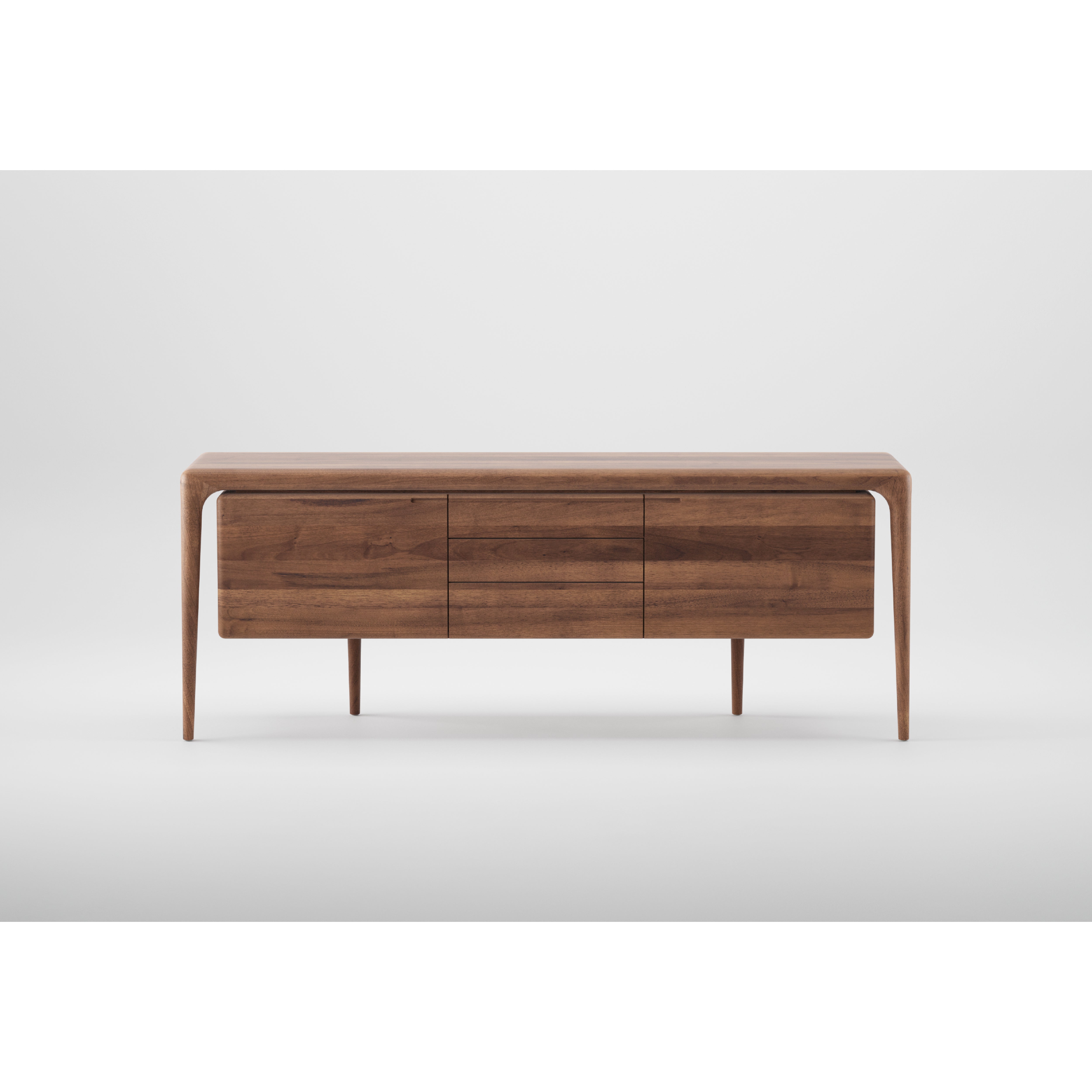The LATUS Sideboard by Artisan is a modern rectangular piece crafted from solid wood with sleek lines and minimalistic design. It features three drawers, stands on four slim legs, and boasts a smooth finish enhanced by natural oils, all set against a plain white background.