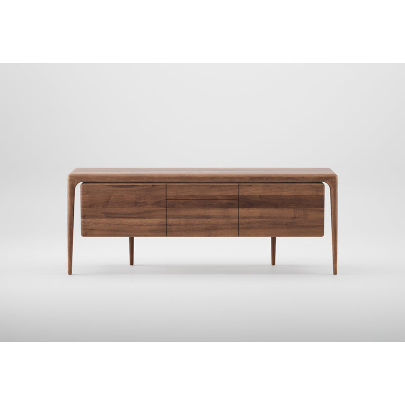 The LATUS Sideboard by Artisan is a modern rectangular piece crafted from solid wood with sleek lines and minimalistic design. It features three drawers, stands on four slim legs, and boasts a smooth finish enhanced by natural oils, all set against a plain white background.