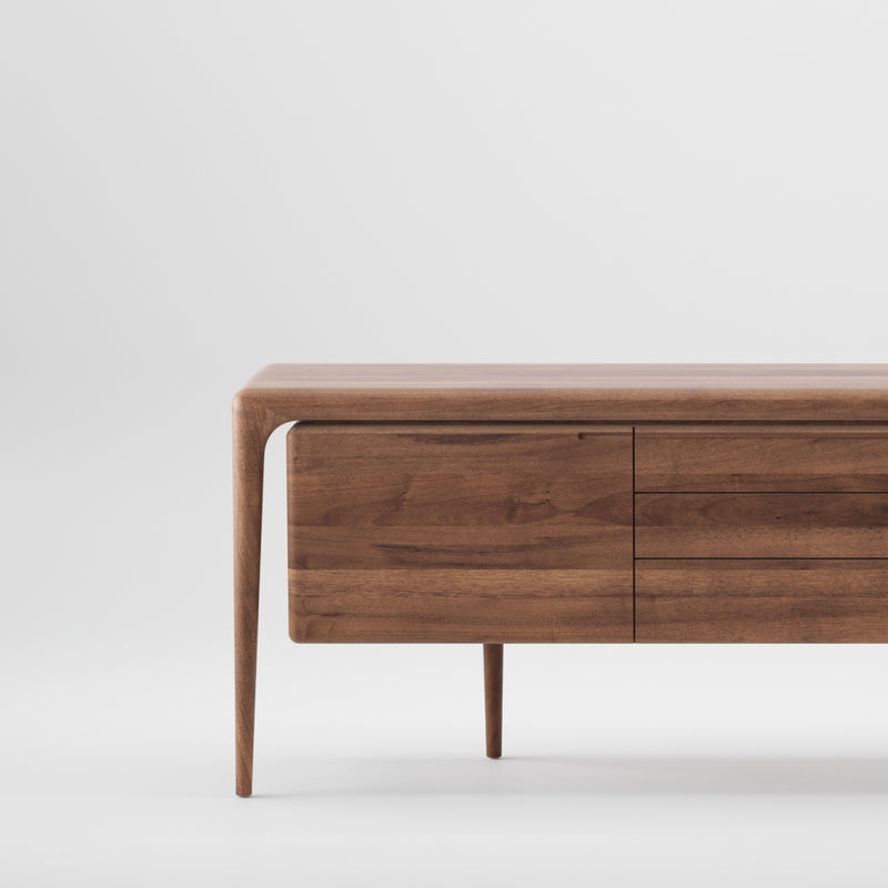 The LATUS Sideboard by Artisan is a minimalist, rectangular wooden piece crafted from solid wood, featuring a smooth surface, two thin legs, and two drawers. Finished with natural oils for eco-friendliness, it displays a subtle grain pattern against its plain white background.