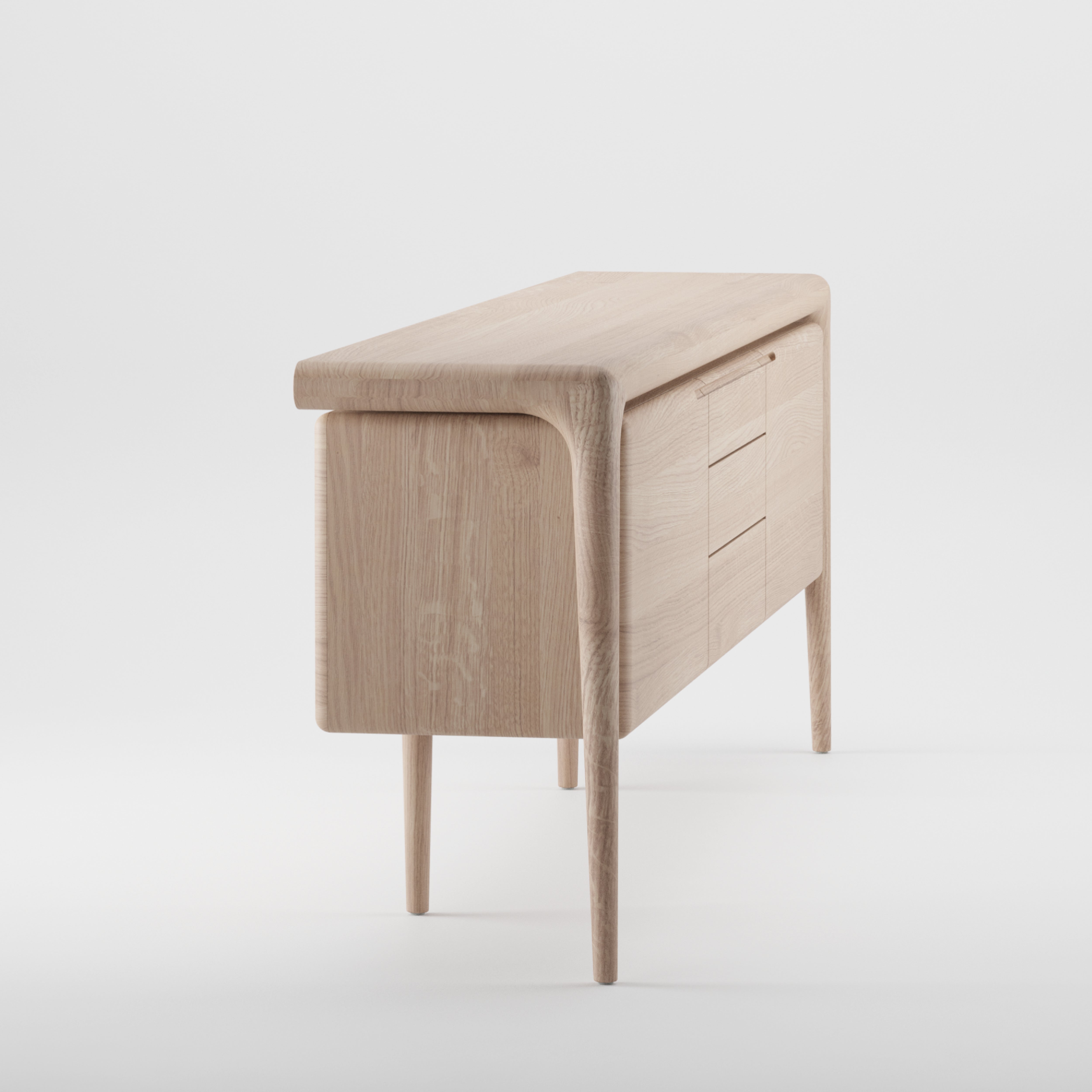 The LATUS Sideboard by Artisan showcases a minimalist, sleek design crafted from solid wood. It features smooth curves, four tapered legs, two right-side drawers, and a left-side door. Finished in light wood with natural oils, it stands elegantly against a plain white background.