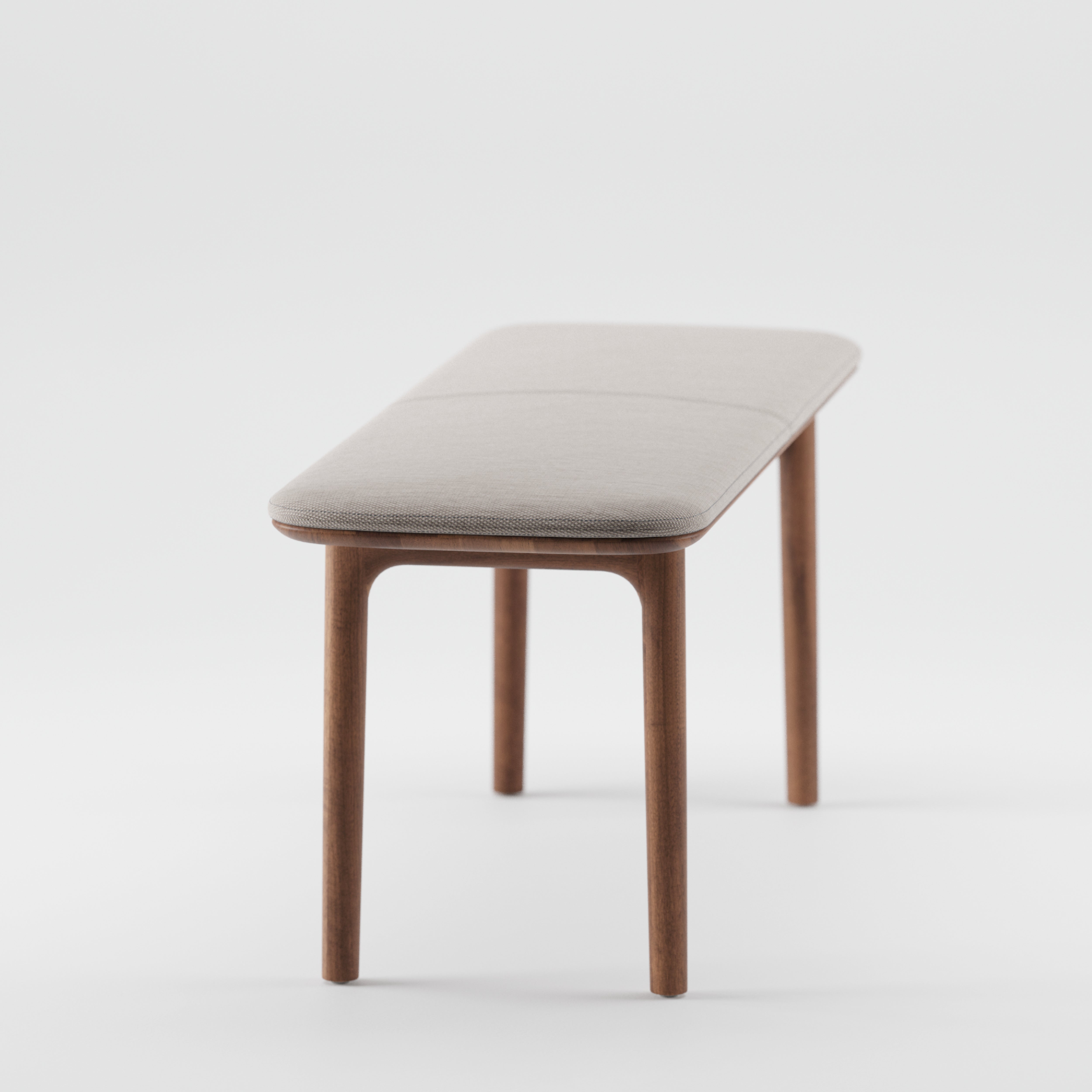 The NEVA Bench by Artisan is a minimalist piece featuring a light gray cushioned seat and four slender legs. Part of the Neva collection, this bench combines modern simplicity with organic wood forms against a white backdrop.