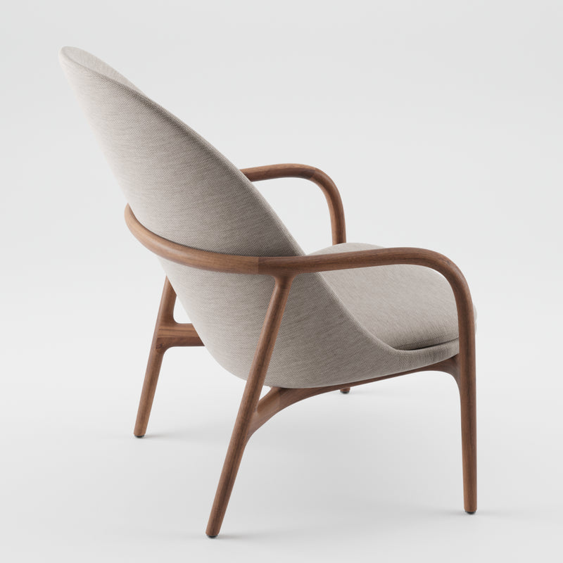 Introducing the NEVA Lounge Chair High by Artisan, a perfect fusion of modern technology and artistry. This chic Scandinavian chair showcases a wooden frame with light gray fabric upholstery, featuring a slightly reclined backrest and smooth, curved armrests on a plain white backdrop.