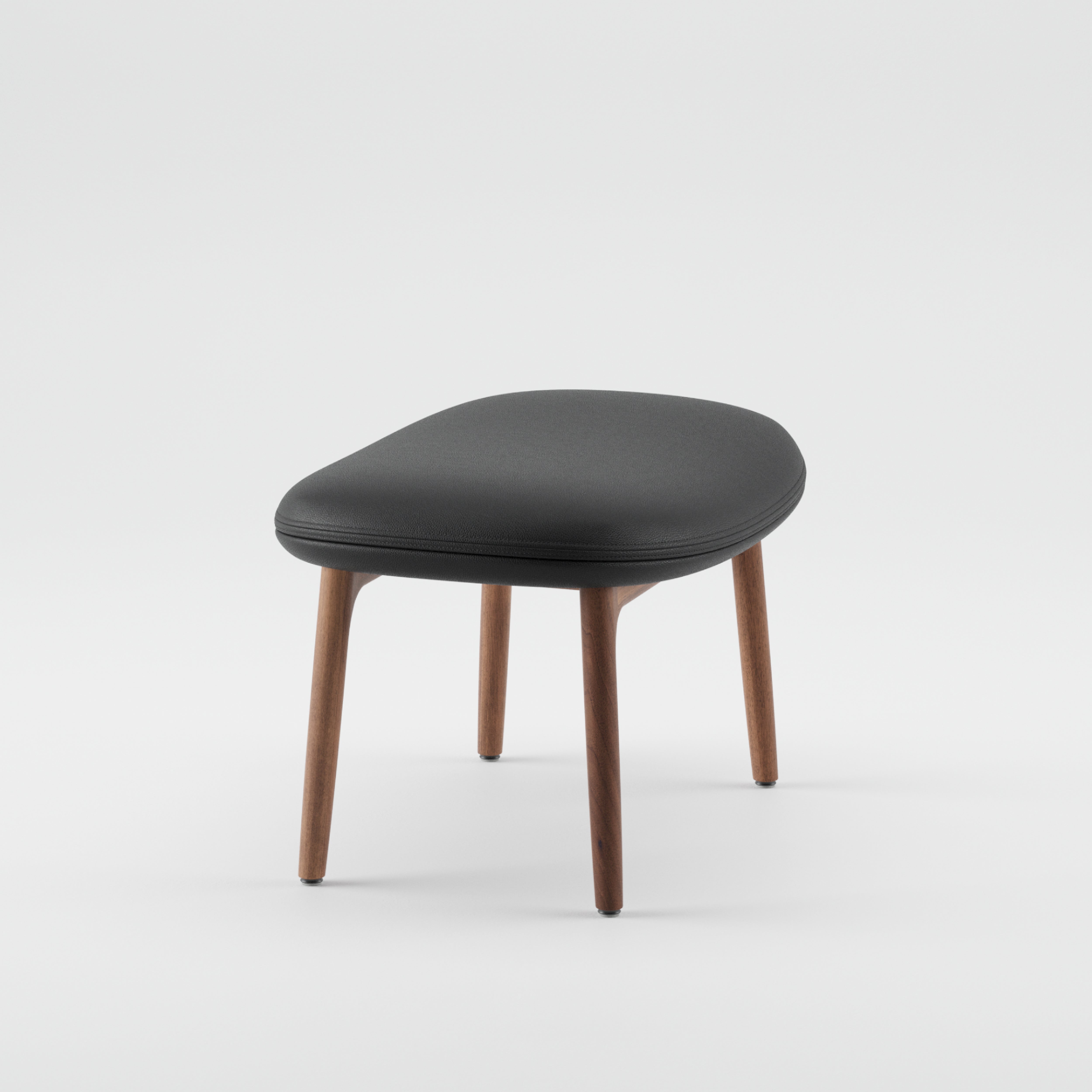 The NEVA Ottoman by Artisan epitomizes Scandinavian lounge furniture with its sleek black cushioned seat and four angled wooden legs, set against a plain white background.
