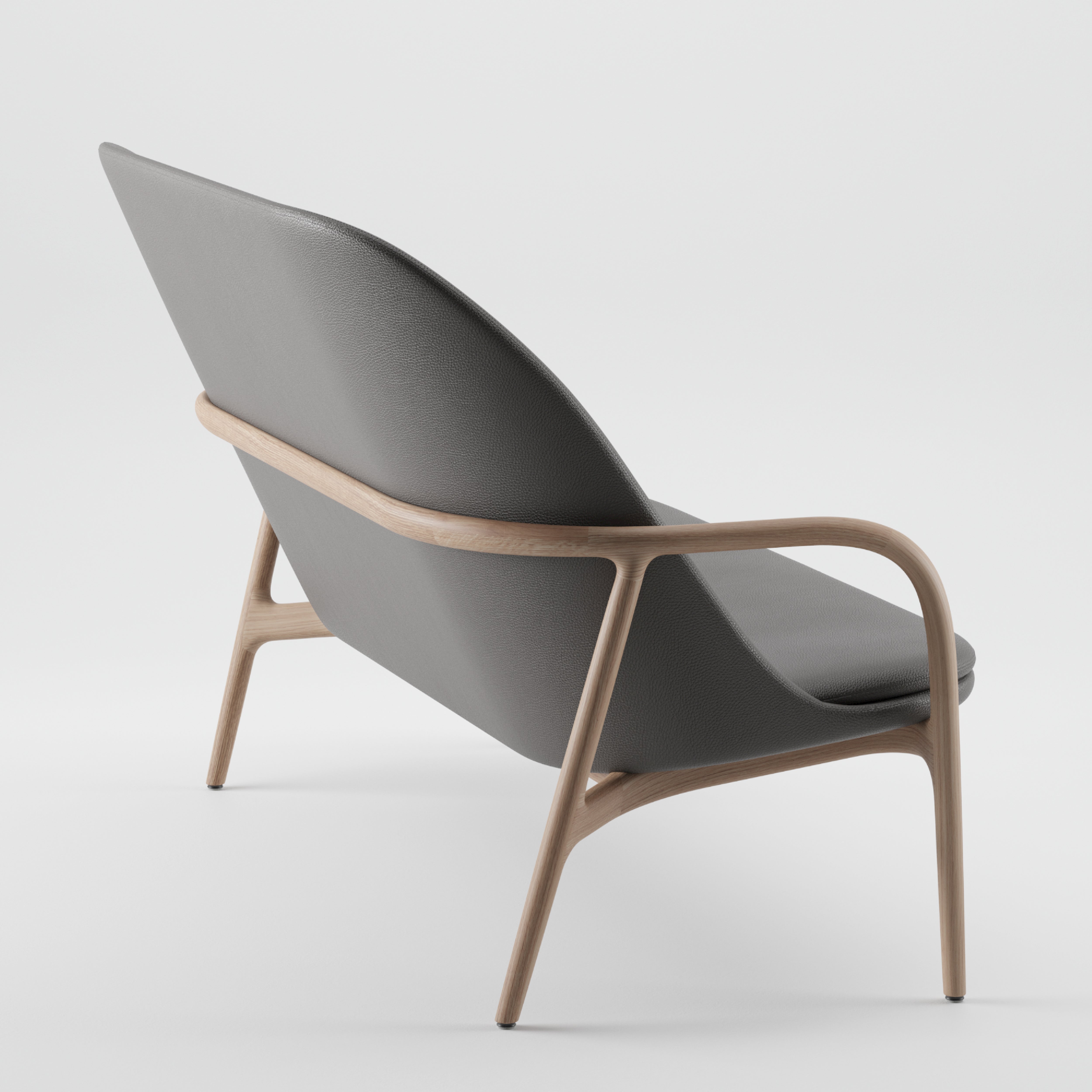 The NEVA Sofa by Artisan showcases a sleek Scandinavian design, featuring a gray upholstered seat and backrest. It has a light wooden frame with smooth, curved armrests and legs, angled to display its side and back profile against a plain white background.