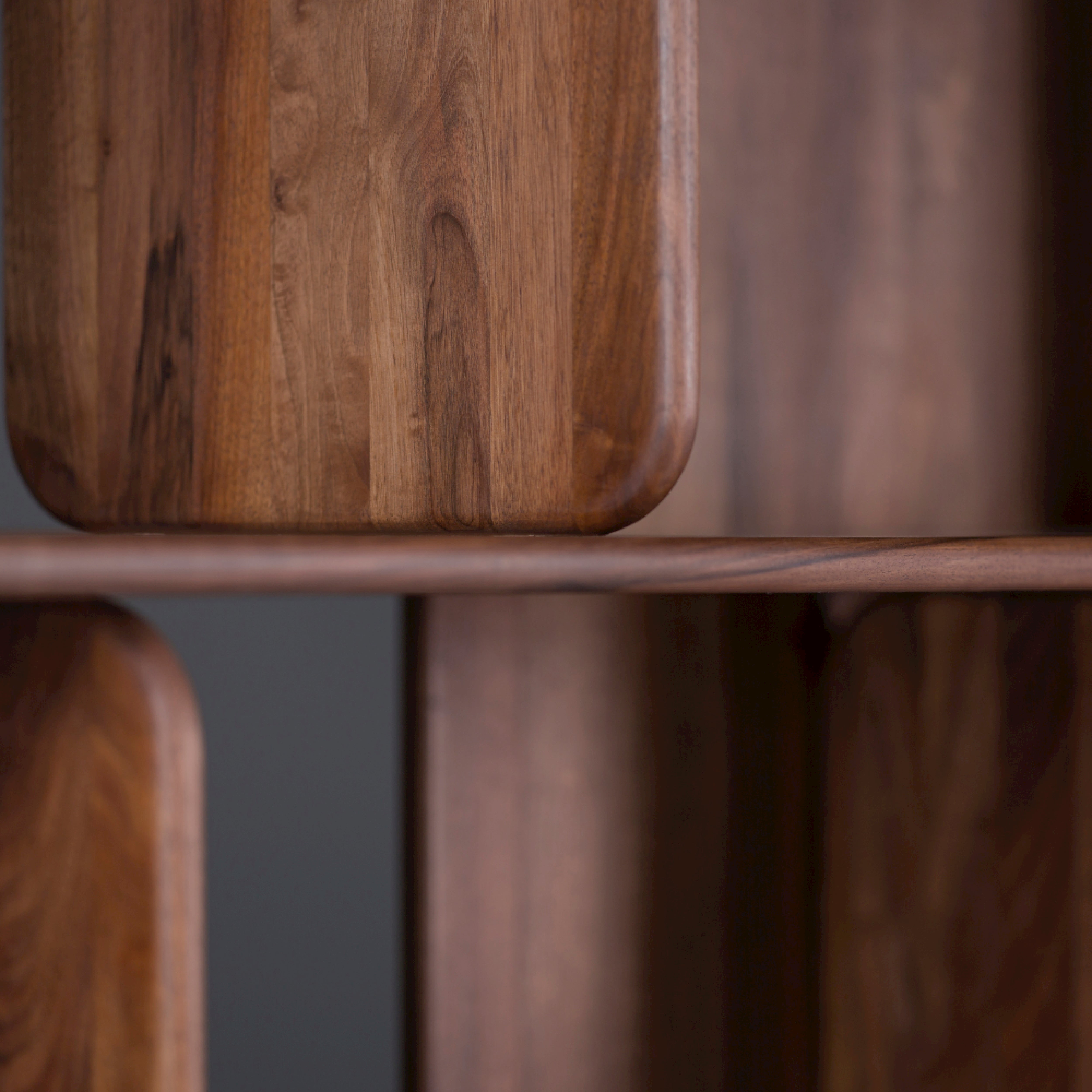A close-up of the Artisan SOFT Shelf reveals solid wood with smooth, rounded edges and a rich grain pattern in dark brown. Its polished look, achieved through natural finishes, gives it a warm, elegant touch.