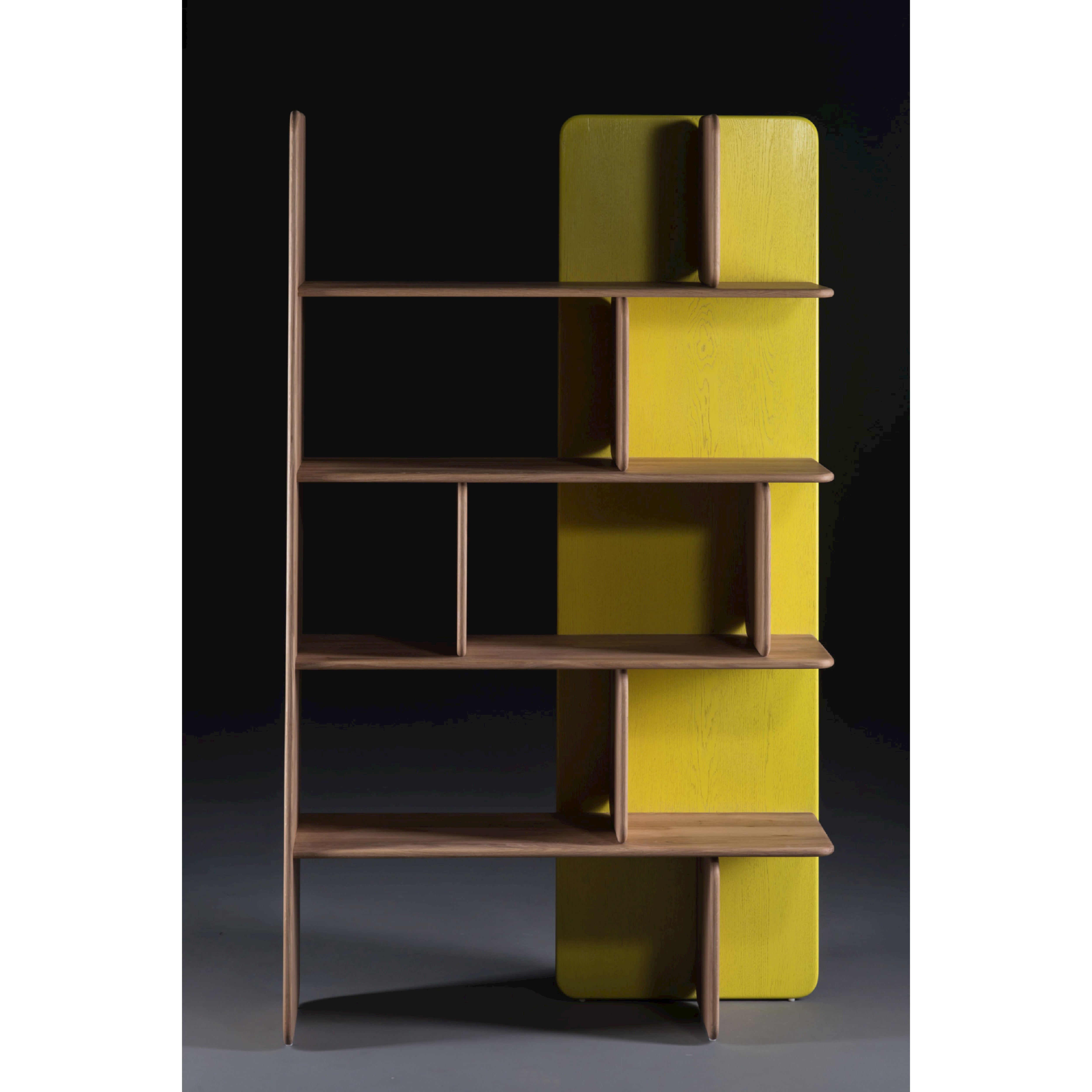 The SOFT Shelf by Artisan is a wooden bookshelf with asymmetrical shelves and a vibrant yellow back panel, crafted from solid wood. It features geometric lines and varied shelf sizes for a modern look, showcasing environmentally-friendly materials against a dark background.
