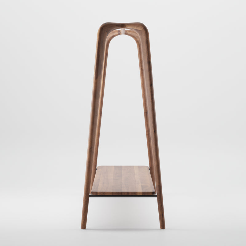 The Artisan SWING Coat Stand is a minimalist piece with a ladder-like design, crafted from solid wood. It showcases a luxurious wood texture and a curved top, featuring one horizontal shelf against a plain white background.
