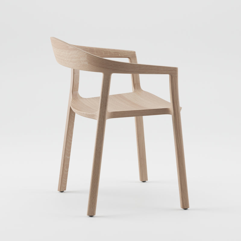 The TARA Armchair by Artisan is a modern wooden chair featuring a sleek, minimalist design with a curved backrest and armrests. Crafted from solid wood and finished with natural oils, it boasts an eco-friendly appeal. It has a light, natural finish and four straight legs against a white backdrop.
