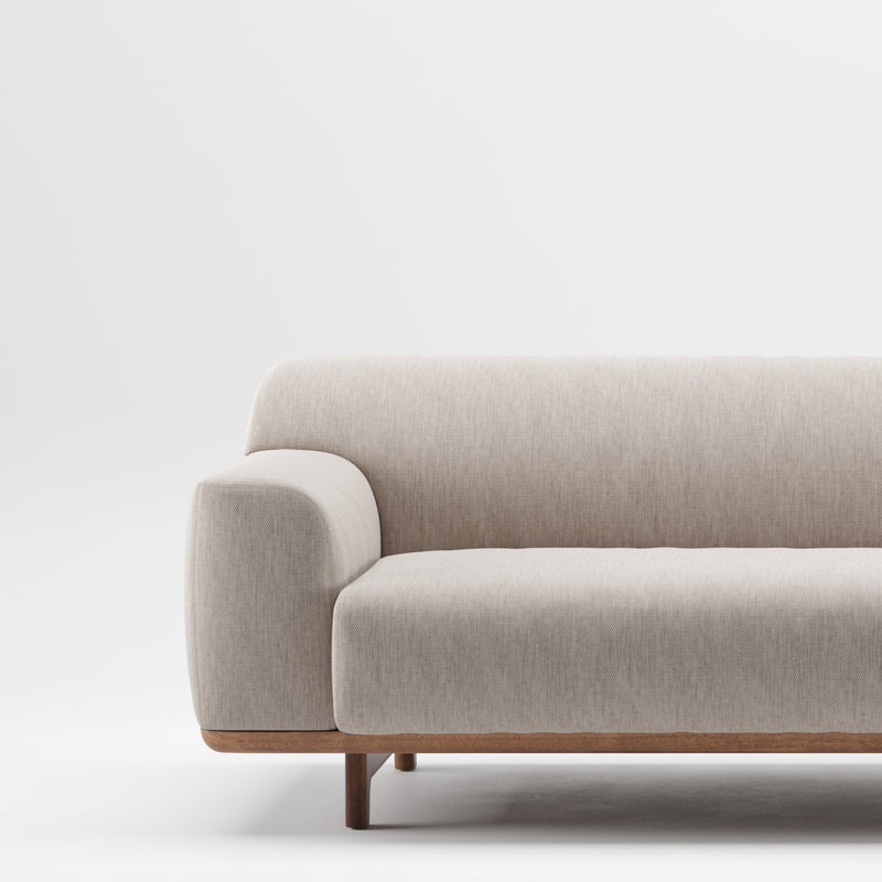 The Tara Sofa by Artisan is a modern, light gray piece with a sleek, minimalist design and solid wood construction. It features rounded armrests and naturally finished wooden legs for an environmentally-friendly touch against a plain white background.