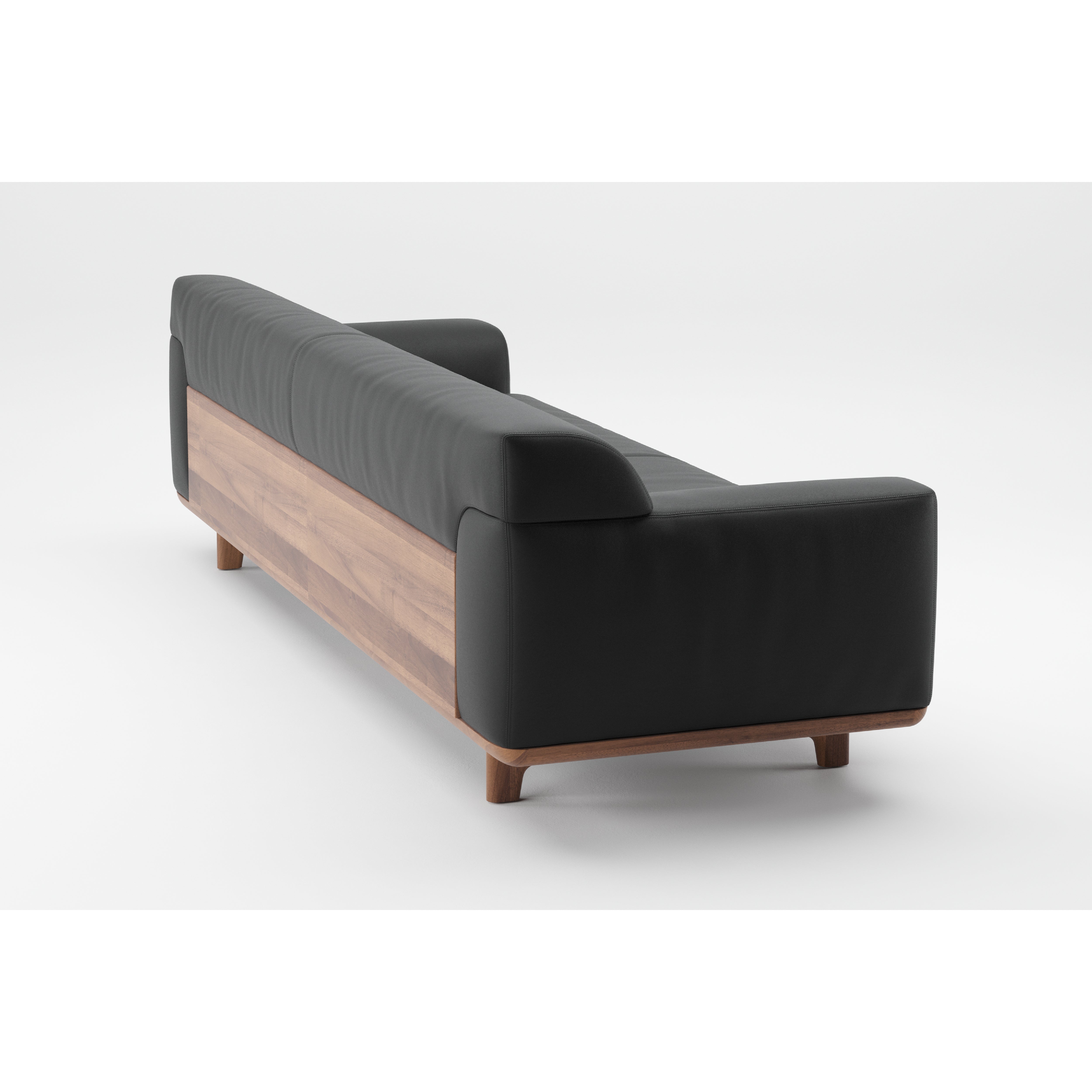 The Tara Sofa by Artisan features sleek black upholstery, a solid wooden back panel, and short wooden legs, all showcased from a rear angle against a white background.