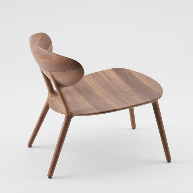 The WU Lounge Chair by Artisan features a minimalist design with a curved backrest and seat crafted from luxury wood textures. It sits atop sleek, angled legs, showcasing the natural wood grain and smooth finish against a plain white background.