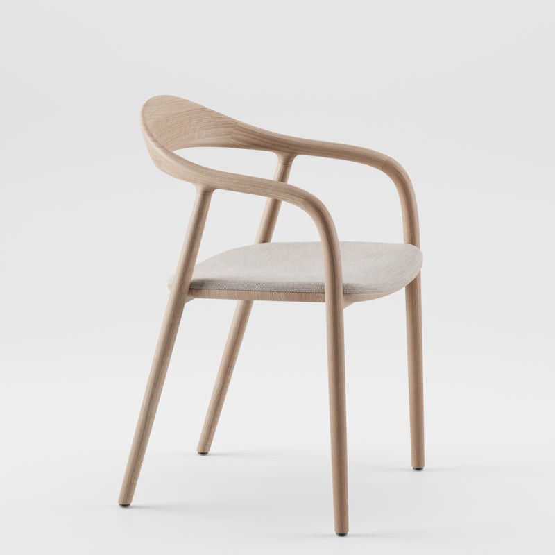 The NEVA chair by Artisan boasts a modern American walnut frame with a curved backrest and armrests. Its light-toned cushioned seat enhances the sleek, minimalist design, expertly crafted using 5-axis CNC technology on a plain white backdrop.