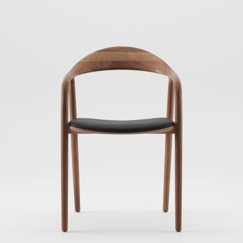 Presenting Artisans NEVA chair: a sleek modern design in American walnut with a curved backrest, armrests, and black cushioned seat. The advanced 5-axis CNC technology enhances its natural wood tones for a flawless minimalist style.
