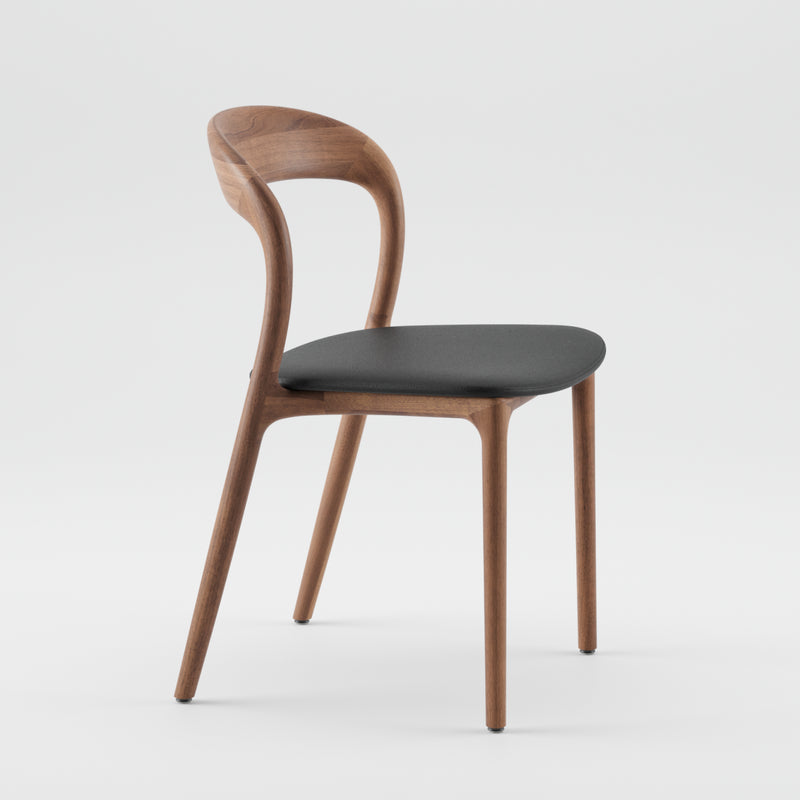 The NEVA light chair by Artisan features a curved backrest and sleek, elegant design. Its dark cushioned seat showcases artisanal craftsmanship and is pictured against a plain white background.