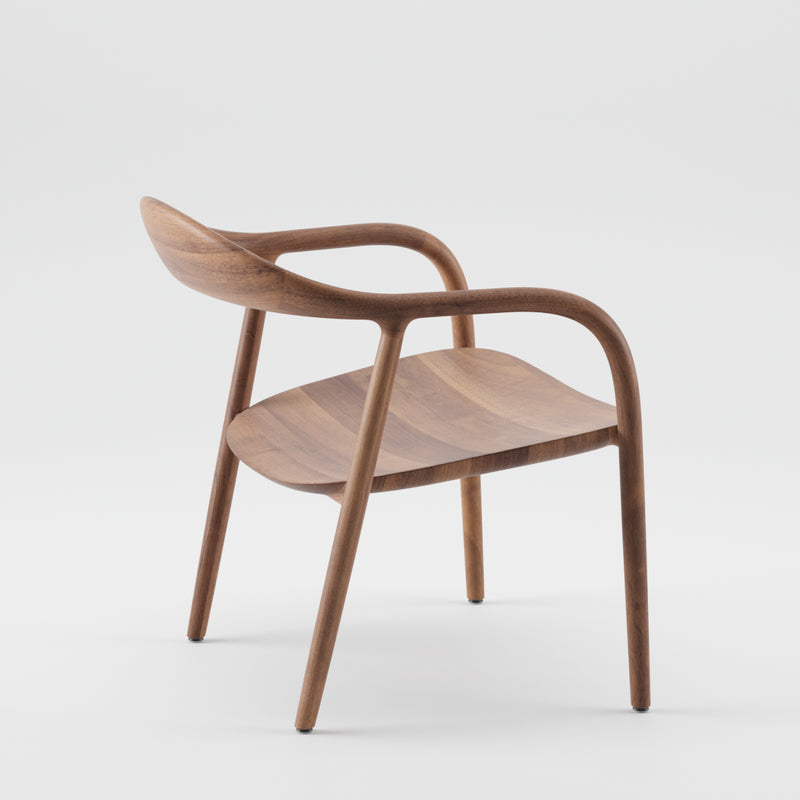 The NEVA Easy Chair by Artisan showcases a modern, minimalist design with curved armrests and a smooth backrest. Crafted using 5-axis CNC technology, the seat and legs are seamlessly integrated from matching wood, embodying elegance and ergonomics against a simple white backdrop.