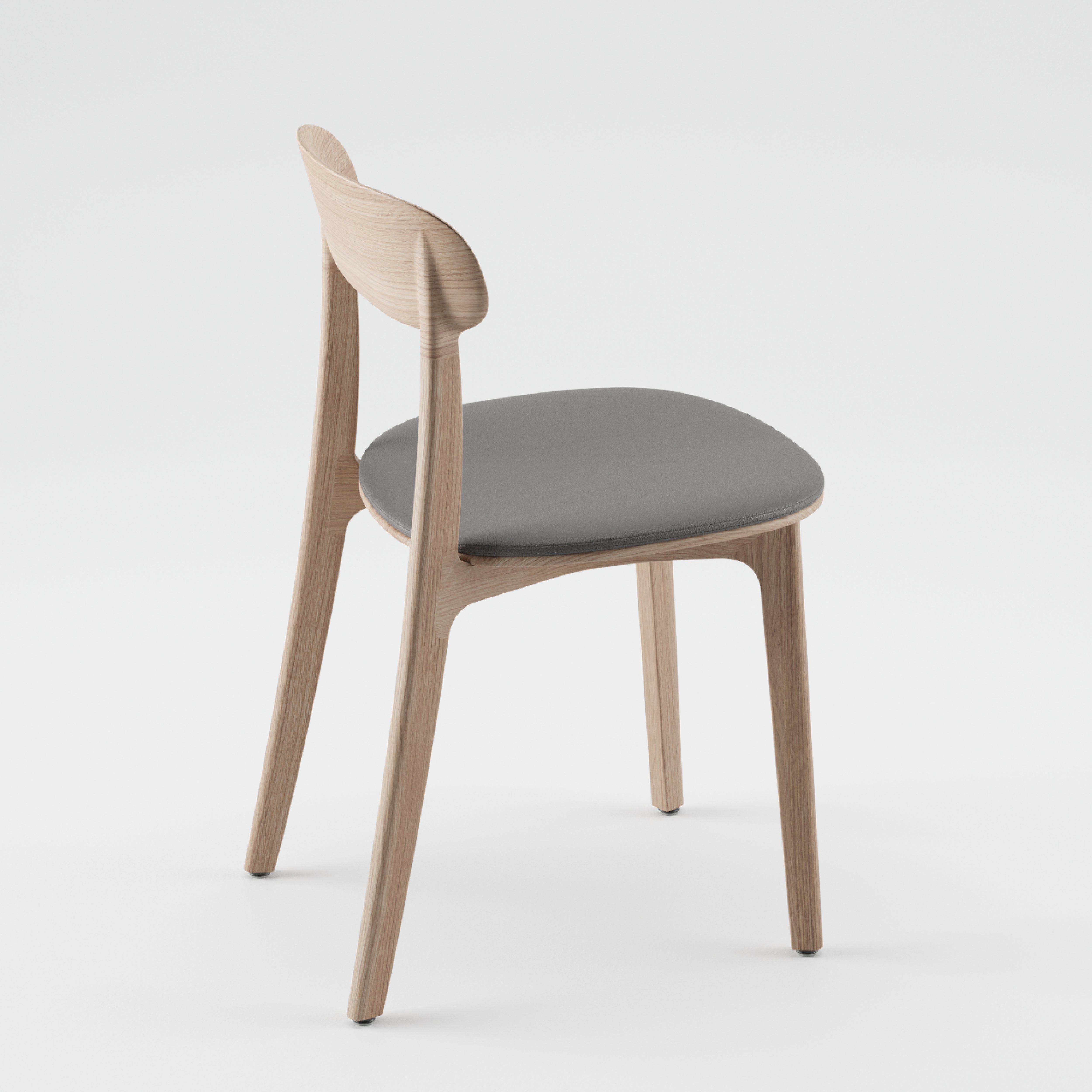 The Artisan TANKA Chair features a modern design with natural finishes, boasting smooth, light wood and a dark gray cushioned seat. It has a curved backrest and slightly splayed legs, blending style and comfort against a plain white background.