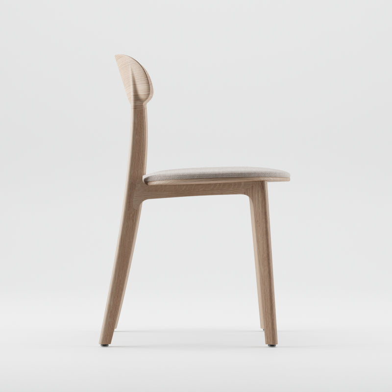 Side view of the Artisan TANKA Chair, showcasing a minimalist design with natural finishes, a light seat cushion, and a solid wood backrest against a plain white background.