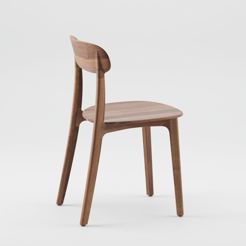 The TANKA Chair by Artisan, with a minimalist design, is showcased against a plain white background. This wooden chair features a curved backrest and four slightly tapered legs, highlighting the natural wood grain finish.