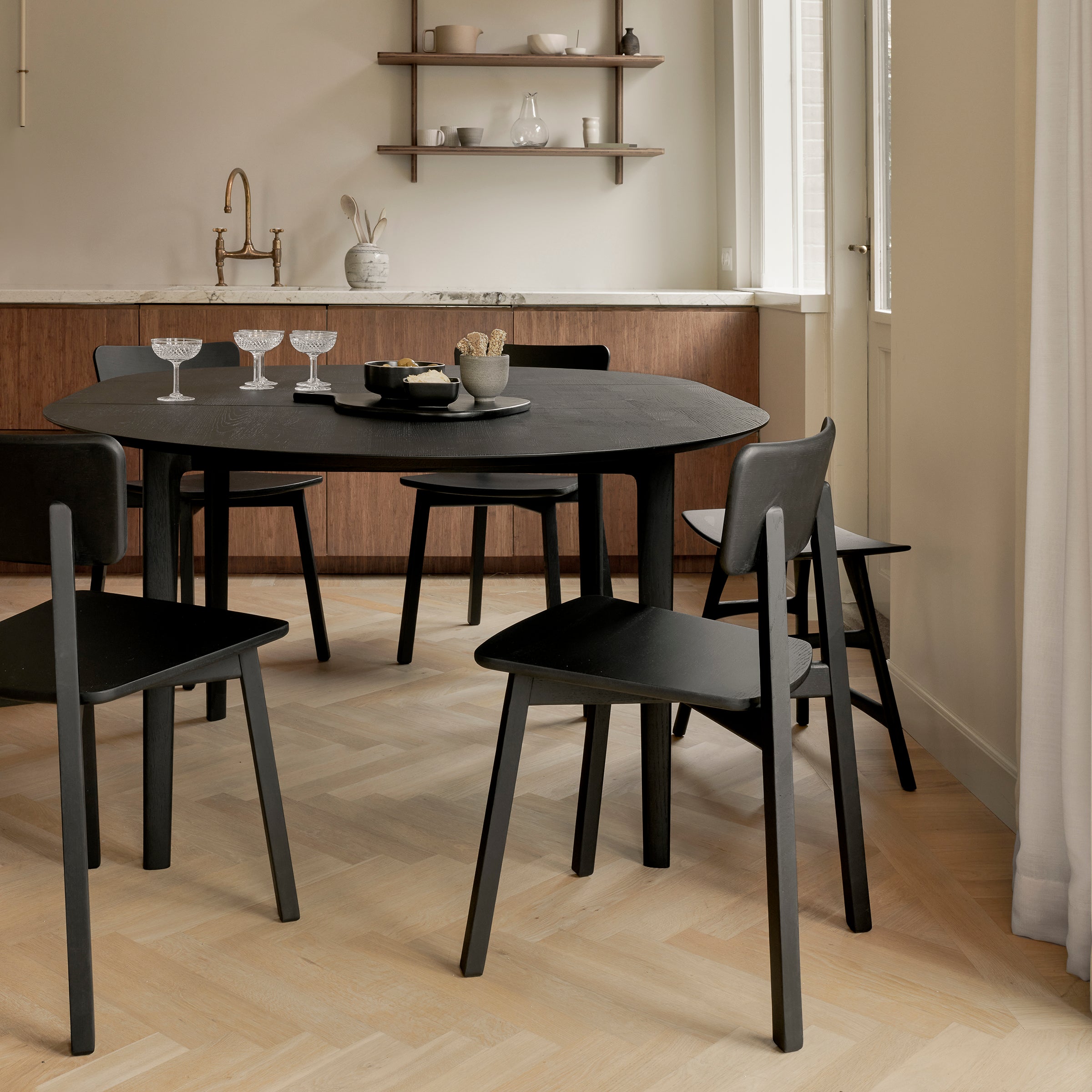 Casale Dining Chair in varnished black oak around a round dining table in modern kitchen setting.