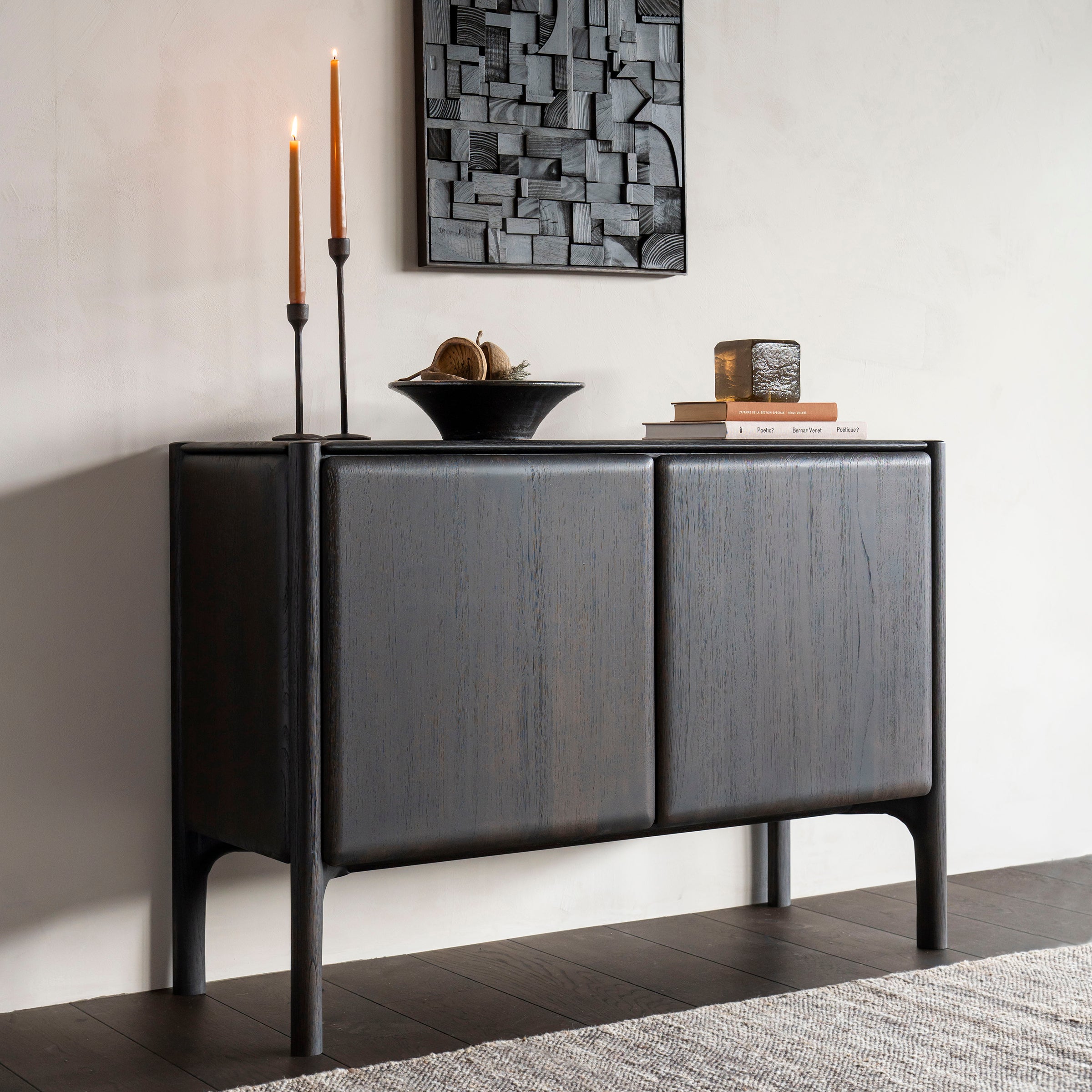 Pi Sideboard in dark varnished teak oak with two doors, minimalist design, styled with candles and decor on top.