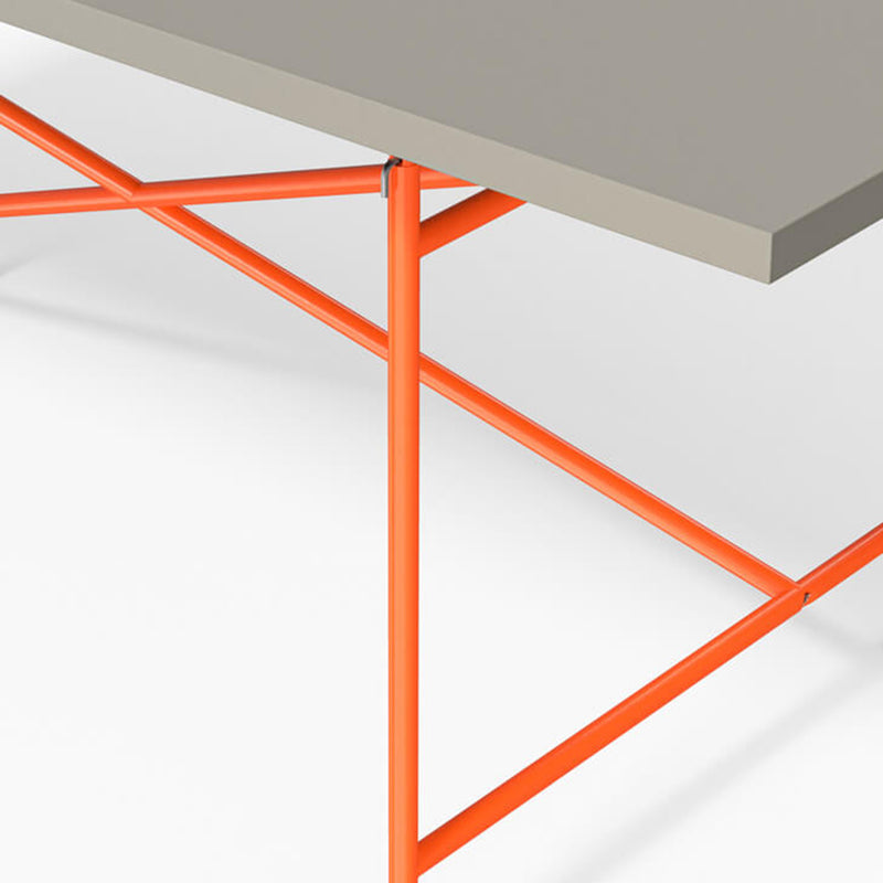 A close-up of the Richard Lampert Eiermann 1 Table shows a gray tabletop with bright orange metal legs in a geometric design against a plain white background.