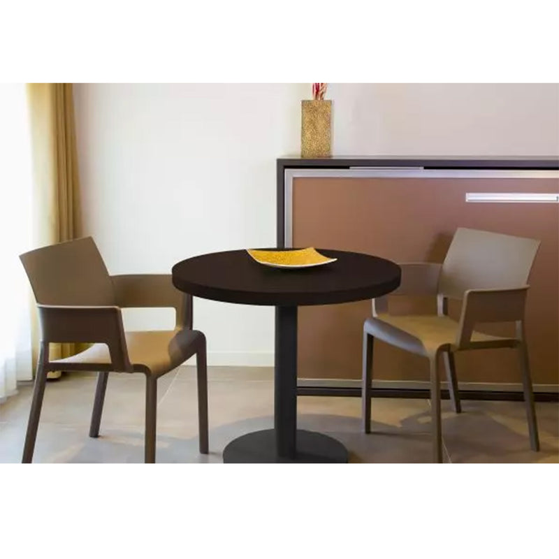 The setting features Resols Barcino Pie Central Round Table, small and round in powder-coated aluminum, with two beige chairs. In the background is a rectangular wall cabinet with a golden vase, highlighting sustainable production and neutral tones with natural left-side lighting.