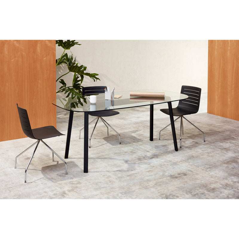 A modern office meeting space features a Noren table by Resol, with a tempered glass top and two sleek black chairs. Against wooden and white walls, a plant adds greenery. The innovative table holds a rolled-up document and a stationery holder, seamlessly blending style with functionality.