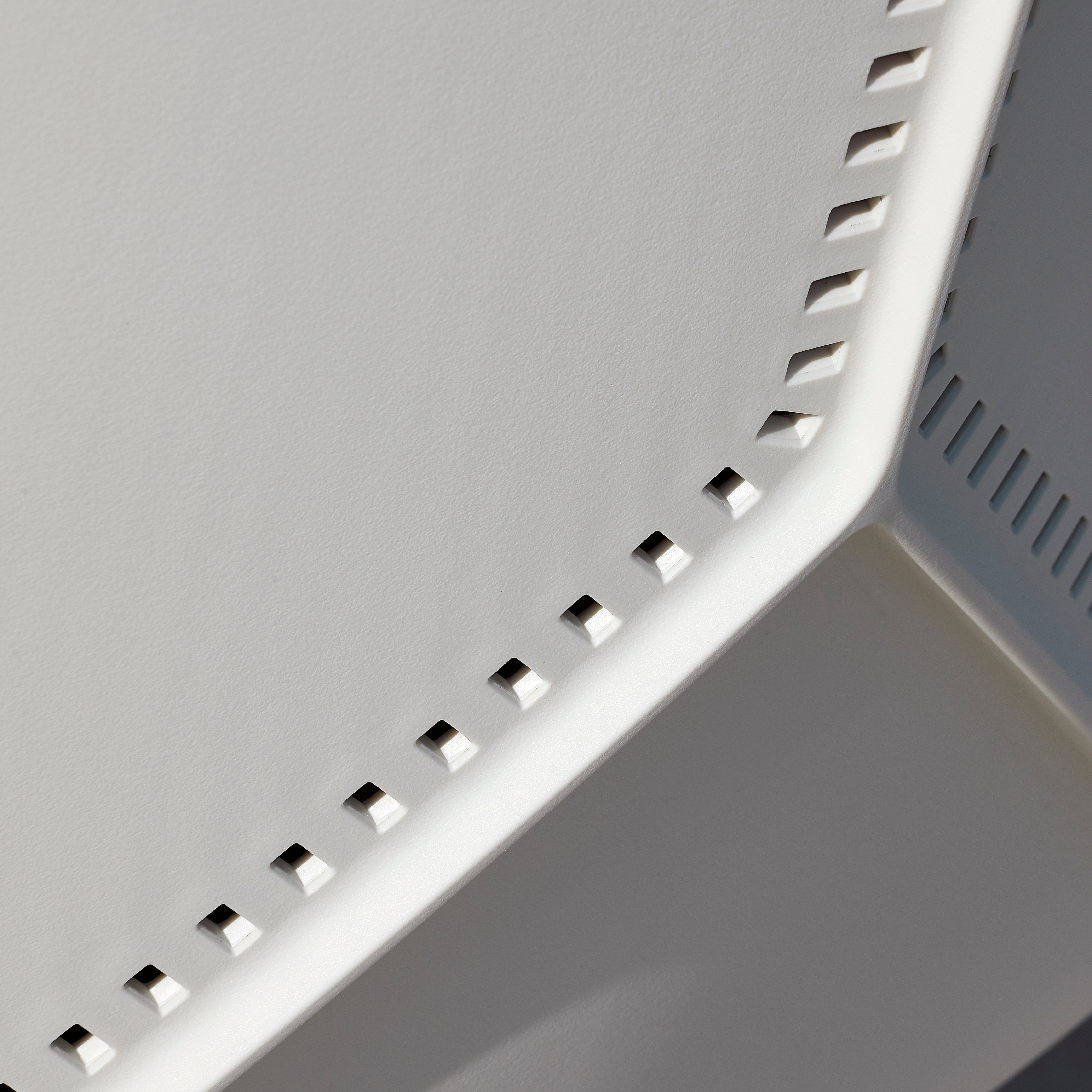 A close-up of an abstract, geometrically patterned polypropylene frame with evenly spaced rectangular cutouts creates a play of light and shadow on the angled structure, echoing the sophisticated lines found in Resols Anou Metal Legs.