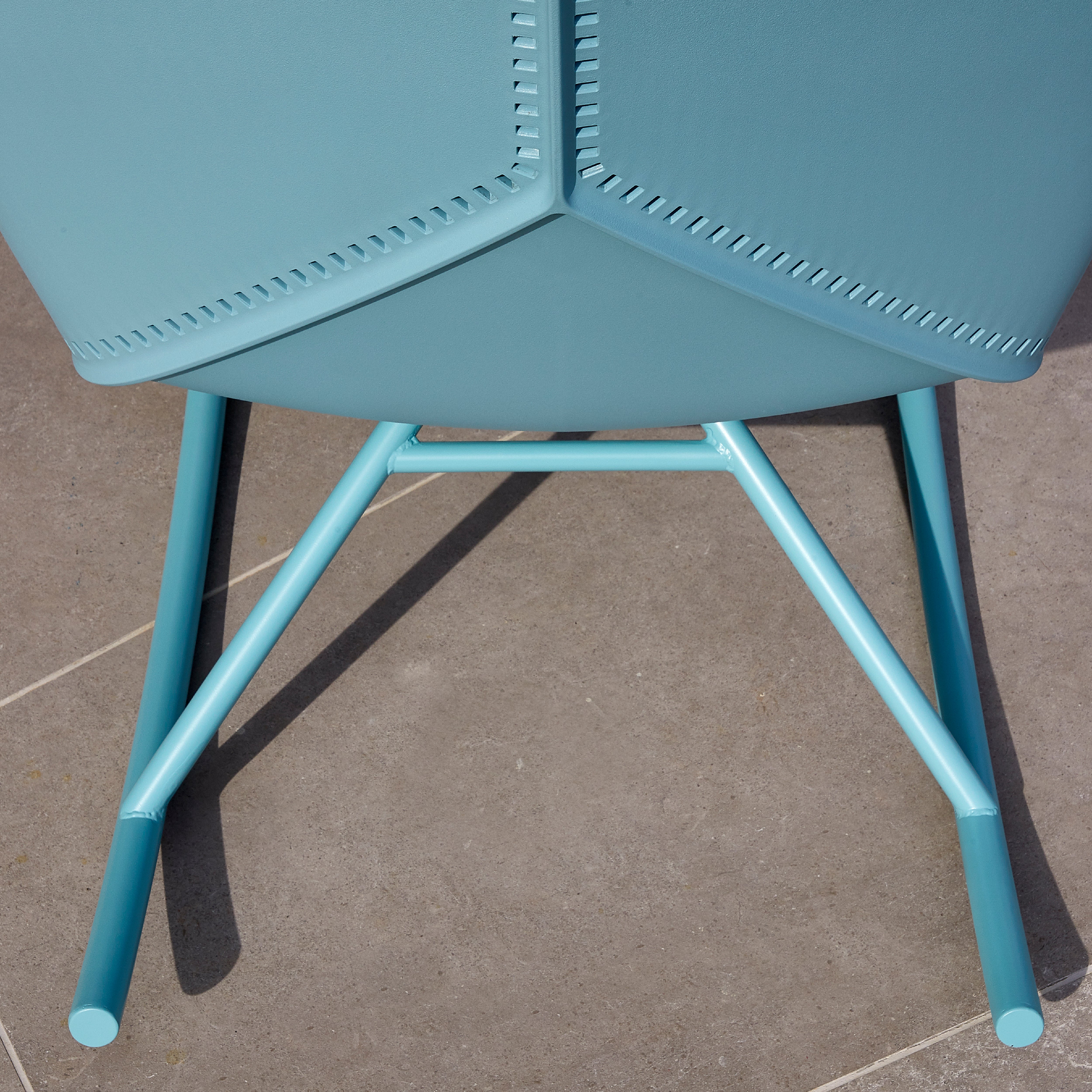 Close-up of a Resol Anou Rocking Chair Legs with a modern design on a stone tile floor. This versatile chair, perfect for both indoor and outdoor settings, boasts a sleek polypropylene frame.