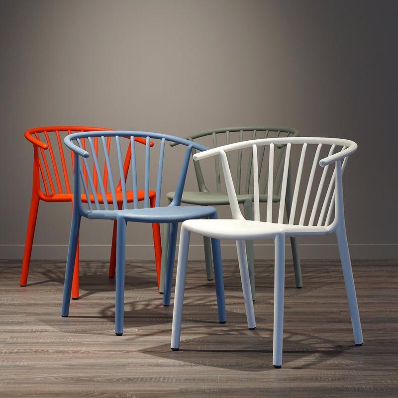 Four Woody Chairs by Resol, featuring rounded backs and open slats, are arranged on a wooden floor. Made sustainably for both indoor and outdoor use, they come in white, blue, green, and orange. Positioned under soft lighting against a plain wall.