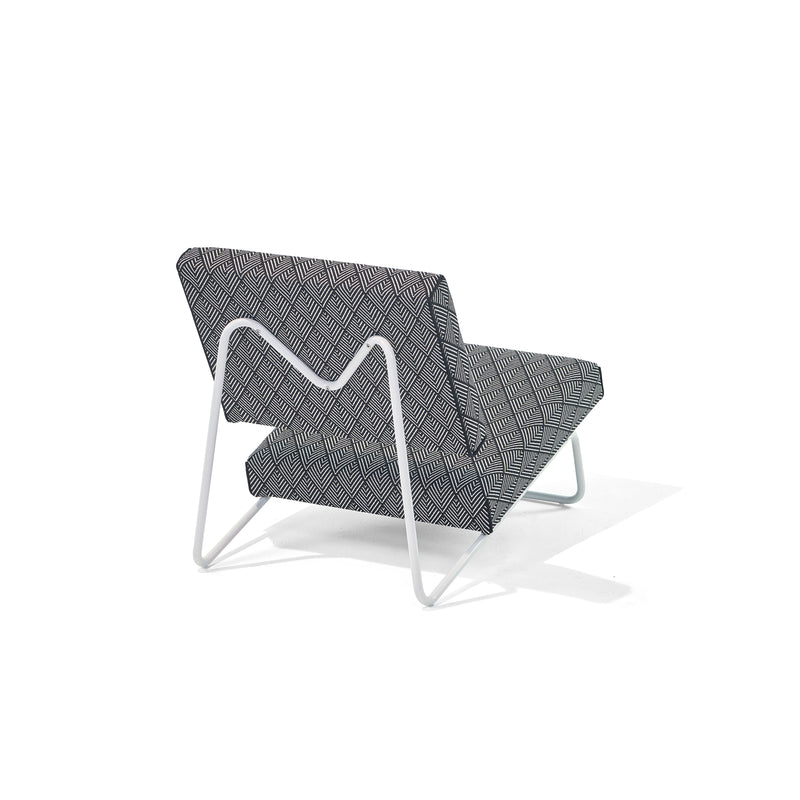 The Hirche Lounge Chair by Richard Lampert showcases a sleek geometric black and white pattern with a Bauhaus-inspired zigzag design and features elegant white metal legs, set against a plain white background.