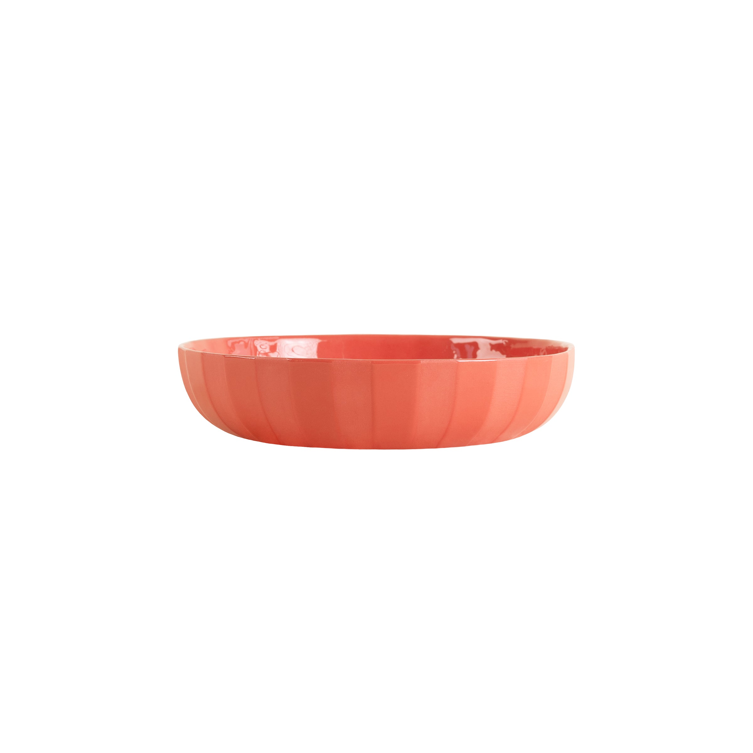 The Facet Tableware - Big Bowl by Schneid is a coral-colored, round ceramic piece with a smooth, glossy finish and slightly ridged texture that enhances its color dynamics against a pristine white background.