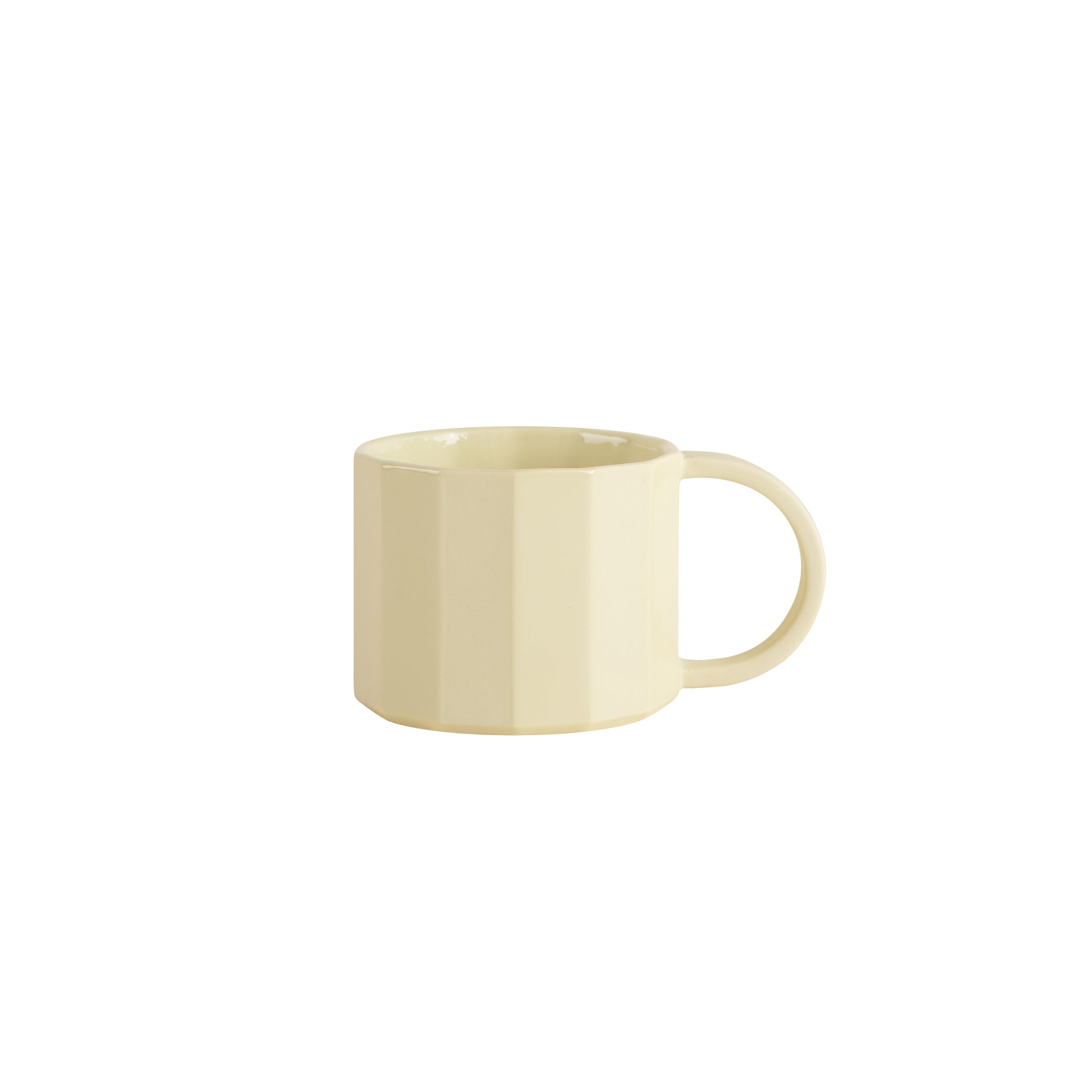 The scene features a pale yellow ceramic mug from Schneids Facet Tableware collection, showcasing its round handle and faceted geometric design against a plain white background.