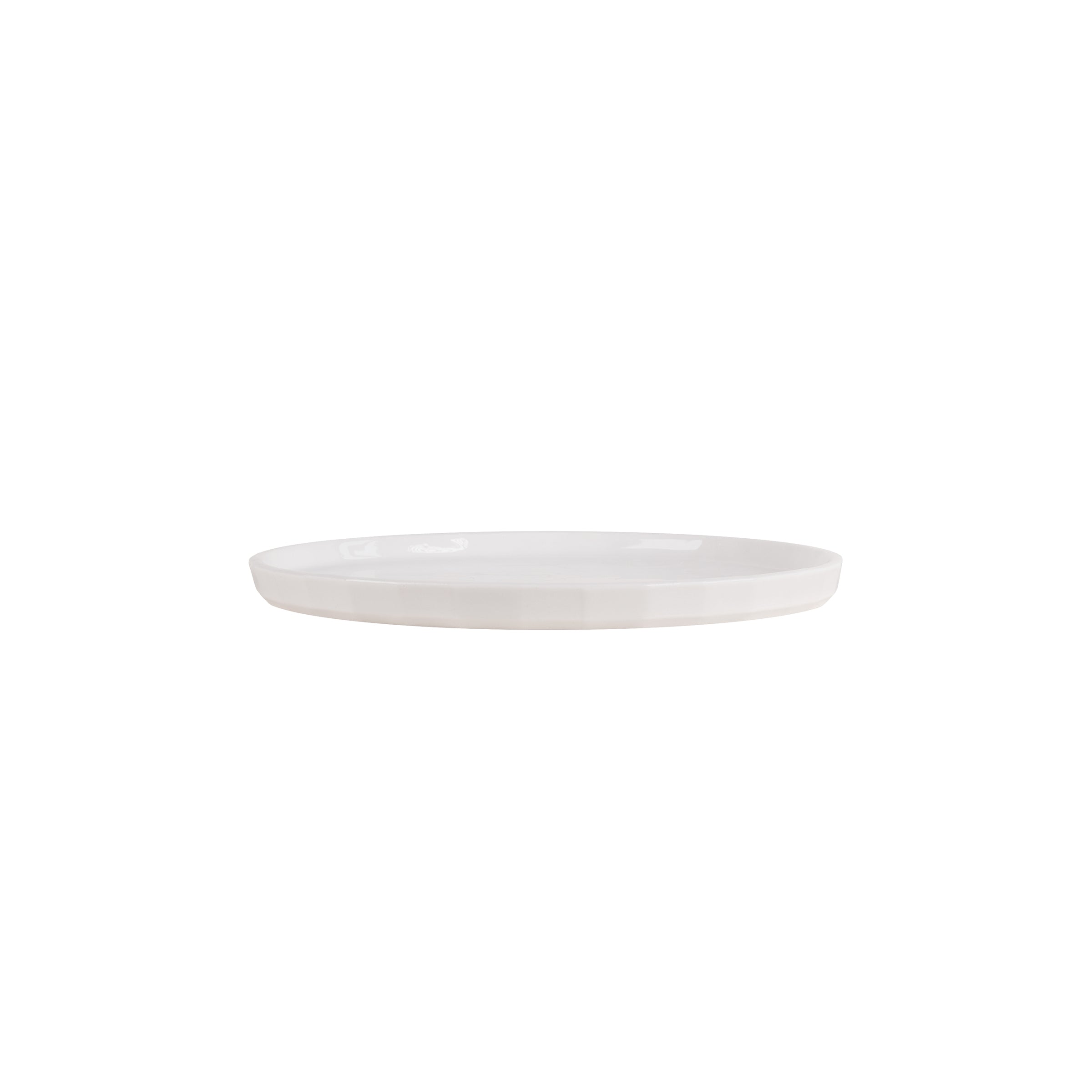 The Facet Tableware plate by Schneid is a plain white, round ceramic dish with a smooth surface, offering a minimalistic design that complements modern aesthetics seamlessly.